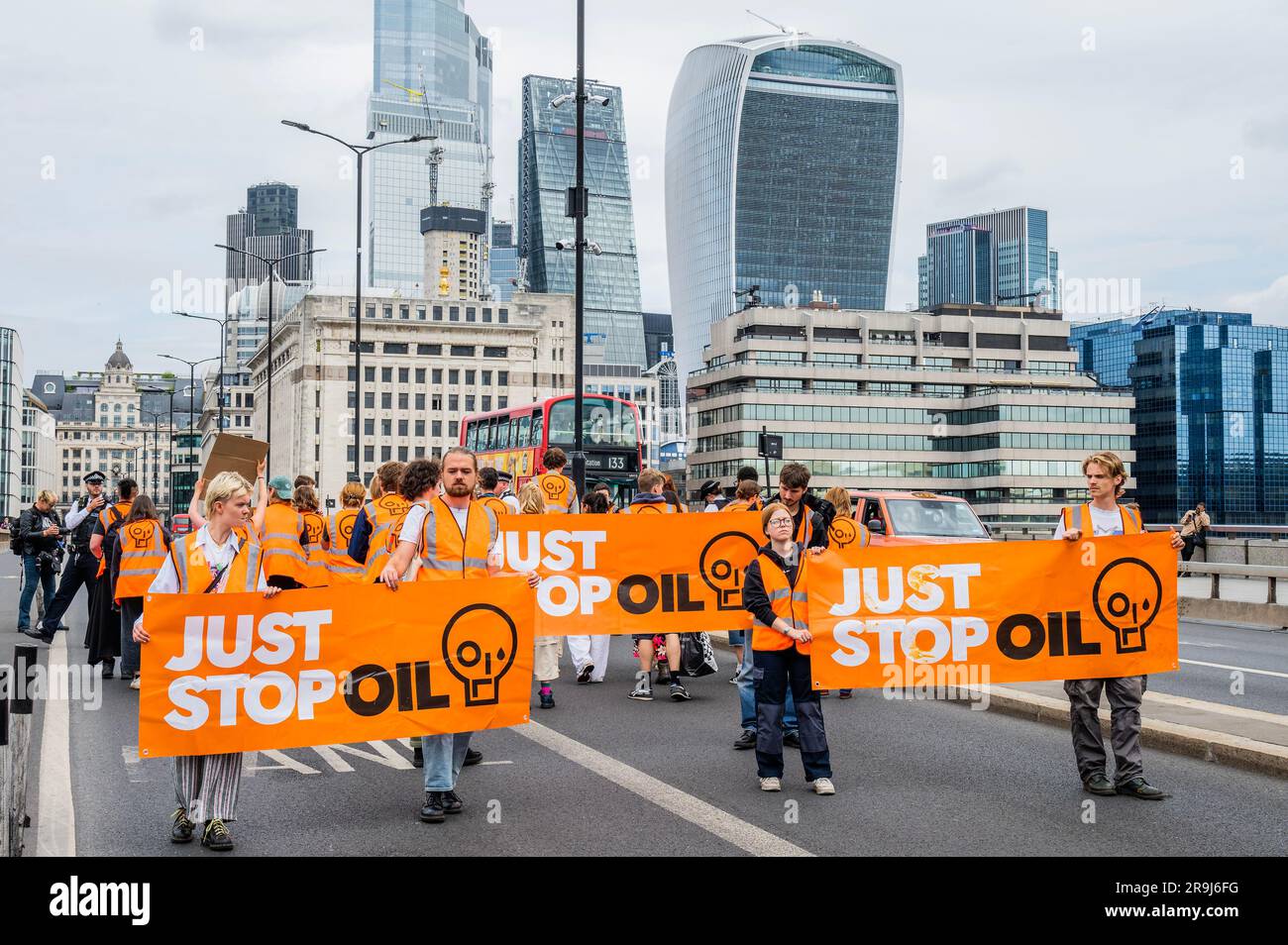 Londra, Regno Unito. 27 giugno 2023. La polizia inizia immediatamente ad avvertire la protesta che stanno bloccando la strada e causando e offendere ai sensi della sezione 12 del Public Order Act - basta fermare la protesta petrolifera al London Bridge. L'obiettivo generale del gruppo è quello di convincere il governo a fermare tutti i nuovi giacimenti petroliferi nell'ambito degli sforzi volti ad evitare la crisi climatica. Crediti: Guy Bell/Alamy Live News Foto Stock