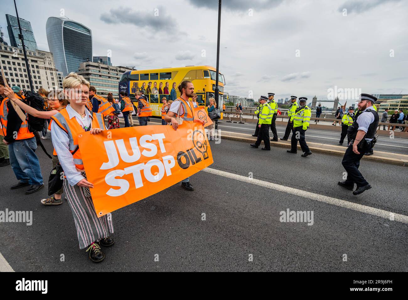 Londra, Regno Unito. 27 giugno 2023. La polizia inizia immediatamente ad avvertire la protesta che stanno bloccando la strada e causando e offendere ai sensi della sezione 12 del Public Order Act - basta fermare la protesta petrolifera al London Bridge. L'obiettivo generale del gruppo è quello di convincere il governo a fermare tutti i nuovi giacimenti petroliferi nell'ambito degli sforzi volti ad evitare la crisi climatica. Crediti: Guy Bell/Alamy Live News Foto Stock