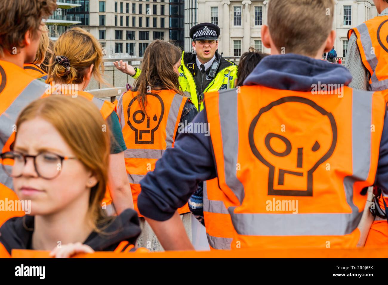 Londra, Regno Unito. 27 giugno 2023. L'ufficiale anziano presente dà un ultimo avvertimento e i manifestanti lasciano la strada dopo averla ammassata a metà del ponte - la polizia aveva già avvertito che stavano causando e offendere ai sensi della sezione 12 del Public Order Act - basta fermare la protesta petrolifera al London Bridge. L'obiettivo generale del gruppo è quello di convincere il governo a fermare tutti i nuovi giacimenti petroliferi nell'ambito degli sforzi volti ad evitare la crisi climatica. Crediti: Guy Bell/Alamy Live News Foto Stock