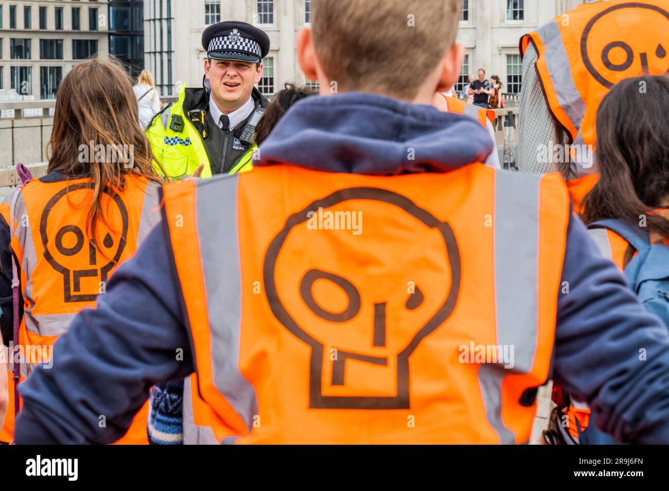 Londra, Regno Unito. 27 giugno 2023. L'ufficiale anziano presente dà un ultimo avvertimento e i manifestanti lasciano la strada dopo averla ammassata a metà del ponte - la polizia aveva già avvertito che stavano causando e offendere ai sensi della sezione 12 del Public Order Act - basta fermare la protesta petrolifera al London Bridge. L'obiettivo generale del gruppo è quello di convincere il governo a fermare tutti i nuovi giacimenti petroliferi nell'ambito degli sforzi volti ad evitare la crisi climatica. Crediti: Guy Bell/Alamy Live News Foto Stock