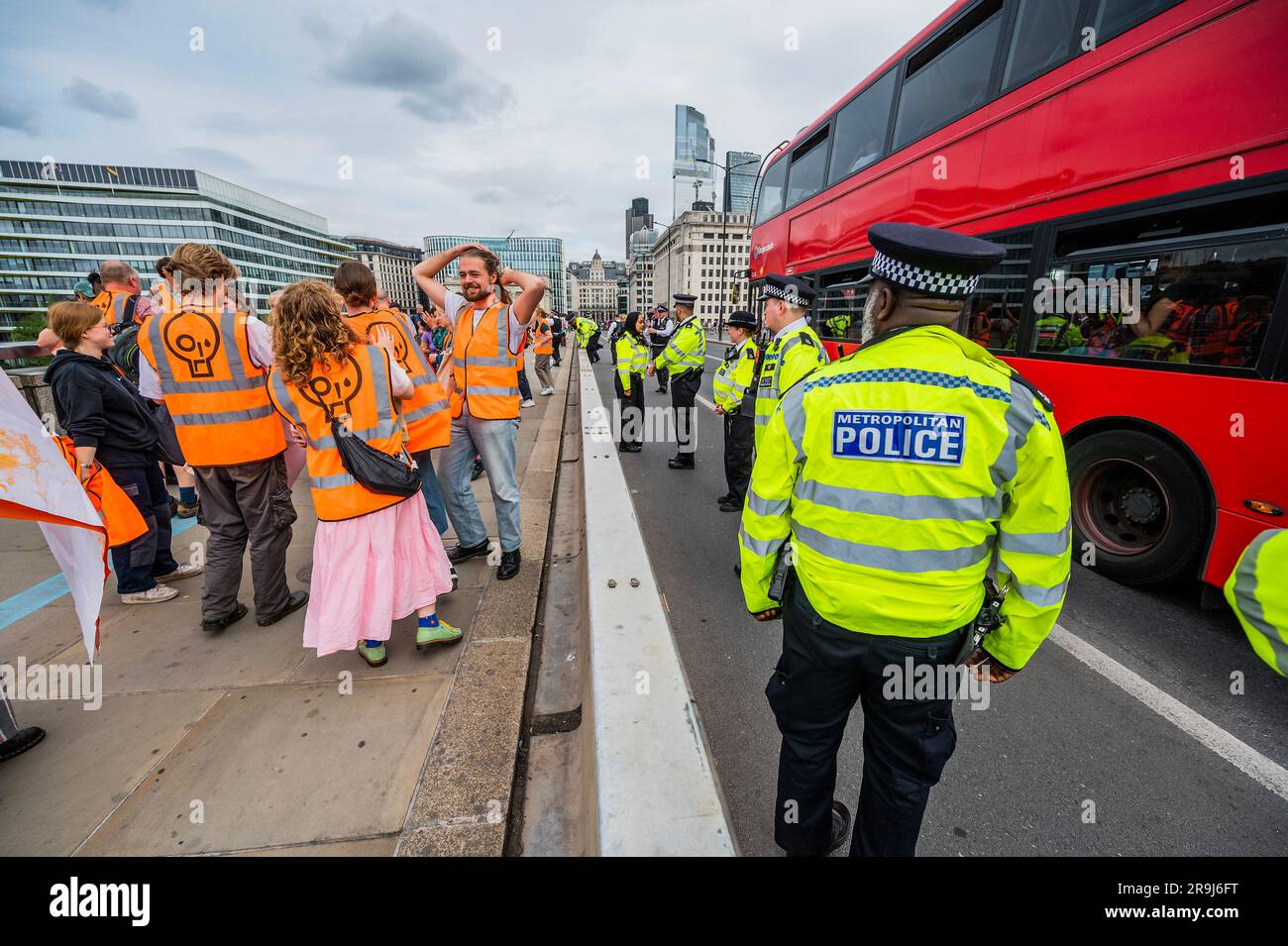 Londra, Regno Unito. 27 giugno 2023. La polizia inizia immediatamente ad avvertire la protesta che stanno bloccando la strada e causando e offendere ai sensi della sezione 12 del Public Order Act - basta fermare la protesta petrolifera al London Bridge. L'obiettivo generale del gruppo è quello di convincere il governo a fermare tutti i nuovi giacimenti petroliferi nell'ambito degli sforzi volti ad evitare la crisi climatica. Crediti: Guy Bell/Alamy Live News Foto Stock
