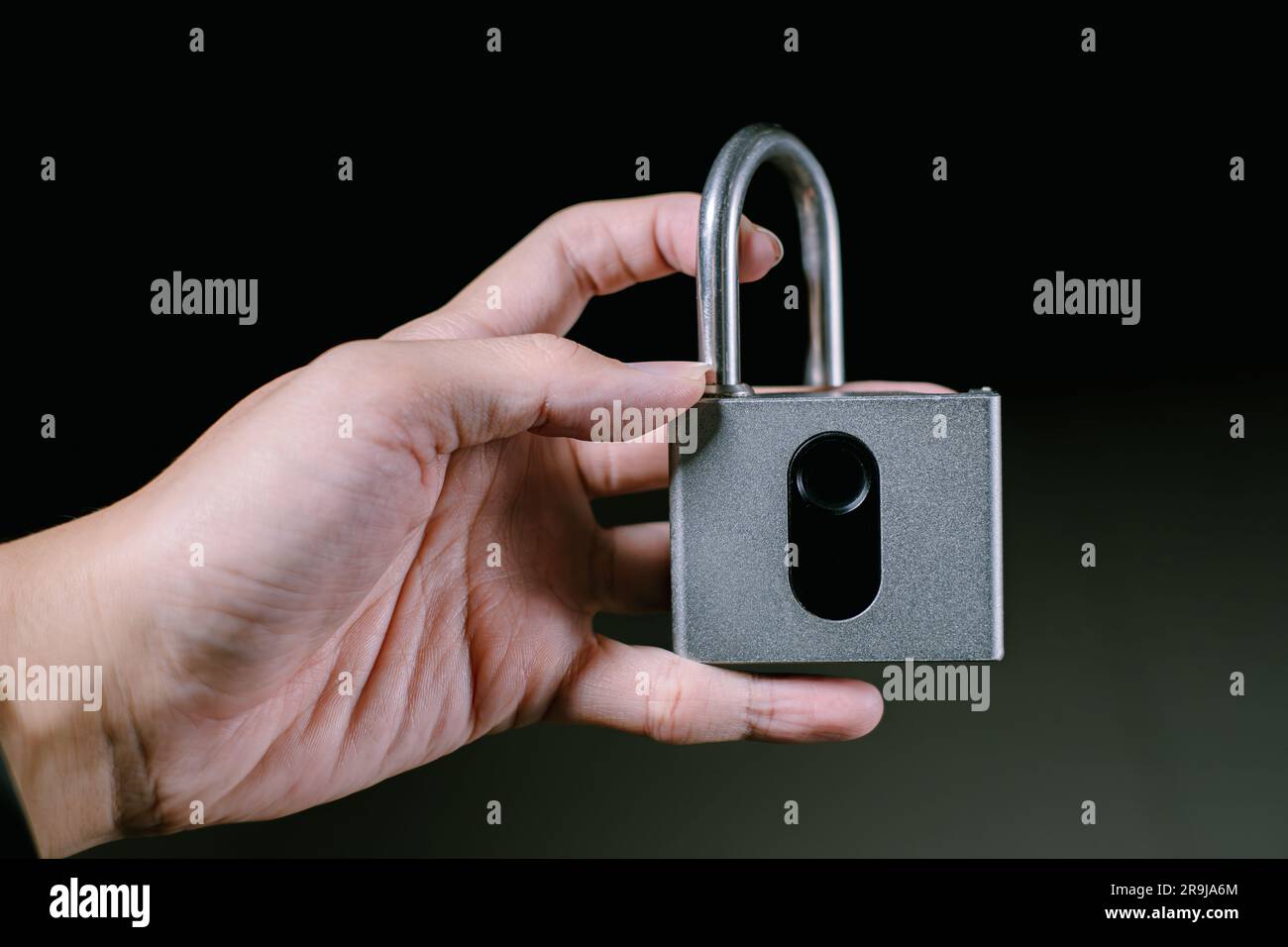 Una mano tiene in mano un lucchetto con impronte digitali sbloccato. Sfondo nero isolato. Adatto per la pubblicità. Foto Stock