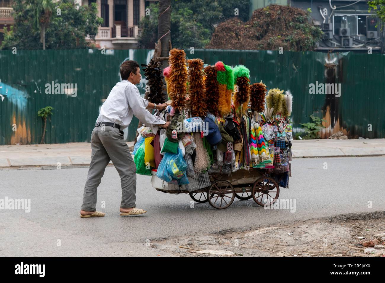 Hanoi, Vietnam-aprile 2023; chiudere un venditore di strada che spinge in vendita un carrello pieno di piume e altri articoli per la casa Foto Stock