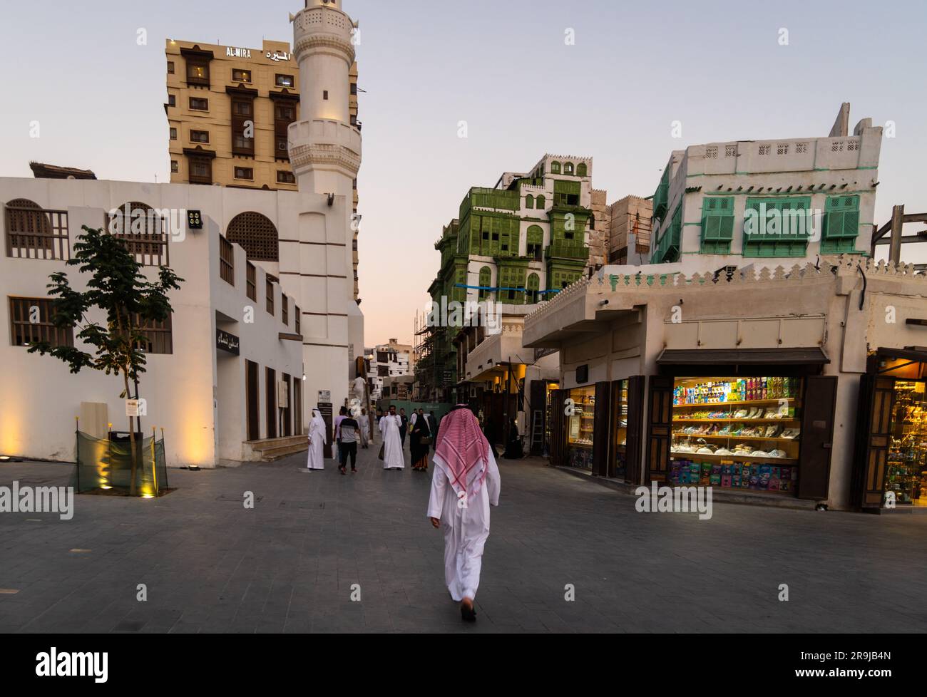 Gedda, Arabia Saudita - persone vestite con abiti tradizionali camminano davanti alla moschea al Ma'amar nella città vecchia di Gedda, al-Balad, in Arabia Saudita Foto Stock