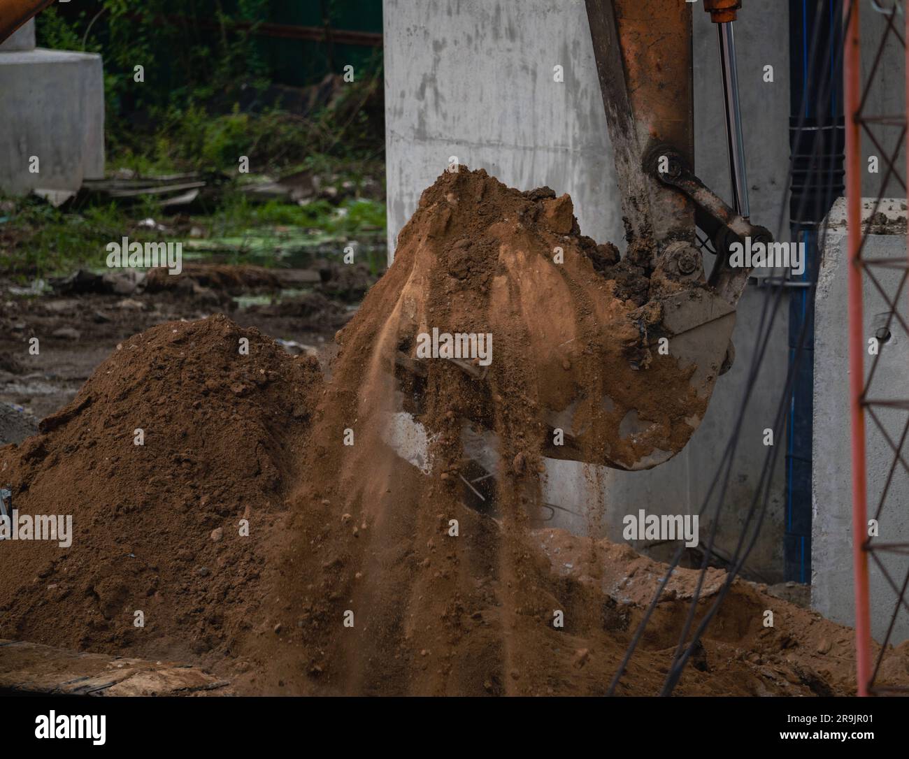 Retroescavatore che opera scavando il terreno in cantiere. Denti della benna del retroescavatore per lo scavo di sabbia. Escavatore cingolato che scava sul terreno. Macchina da scavo. Foto Stock