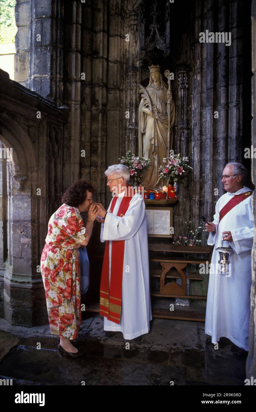 Saint Winefrides Shrine, Holywell. Pellegrino cattolico romano al Santuario di Saint Winefrides il giorno della festa del 22 giugno. Una donna bacia la reliquia di St. Winefride sotto la sua statua. Holywell, Flintshire Wales, UK 1990S. HOMER SYKES Foto Stock