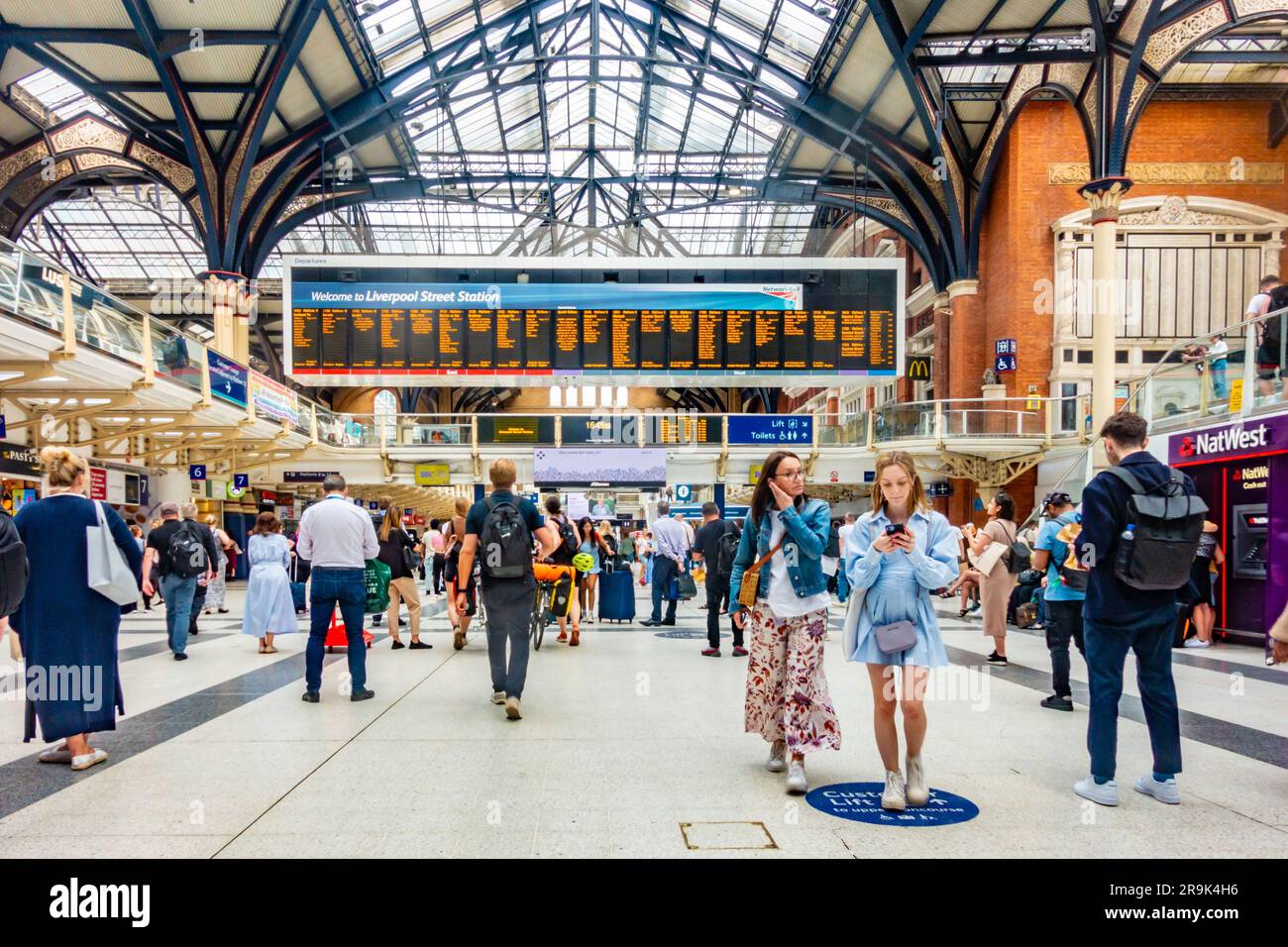 Grande schermo elettronico delle partenze presso la stazione di Liverpool Street a Londra, Regno Unito. La stazione è occupata con i passeggeri. Foto Stock
