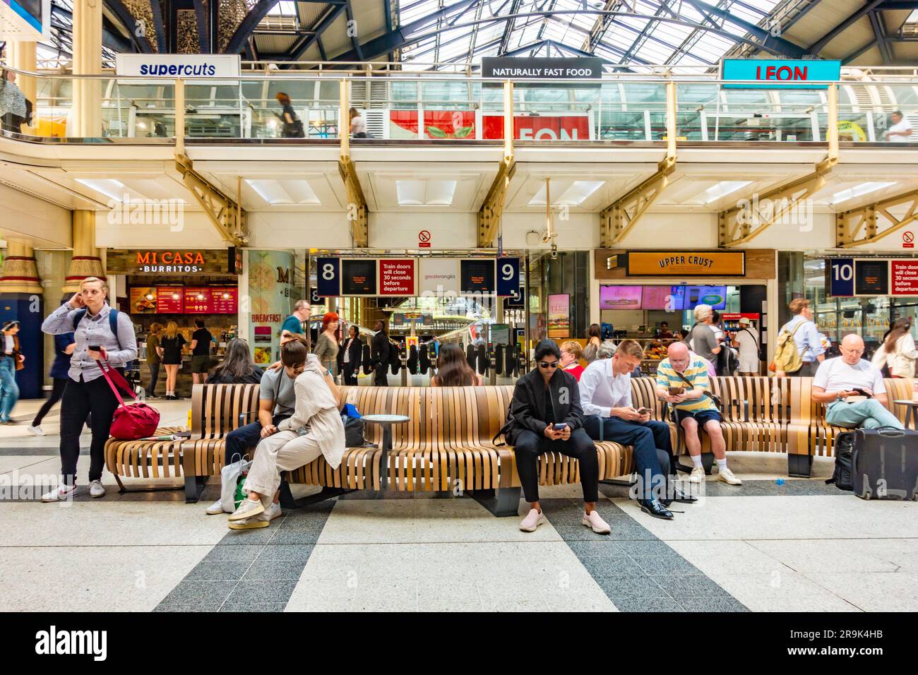 La gente sedeva sulle panchine nell'atrio della stazione di Liverpool Street a Londra, Regno Unito Foto Stock