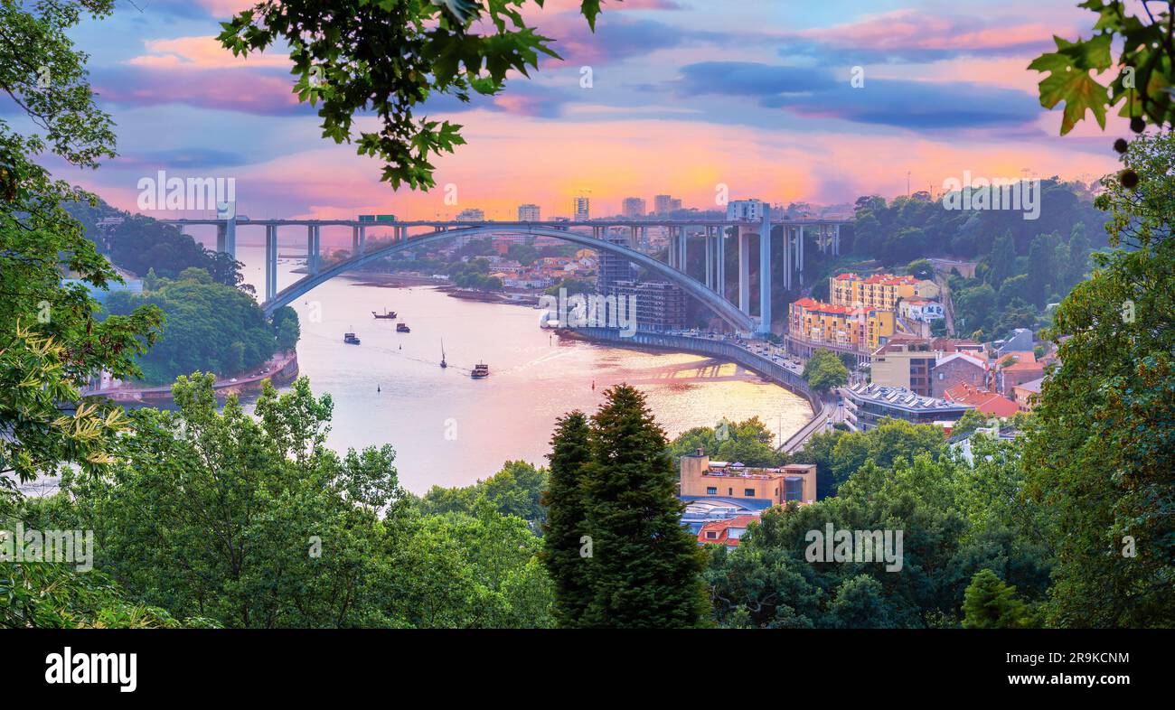 Splendido paesaggio del famoso Arrabida Arch Bridge con escursioni di arrampicata nella città di Porto illuminato al tramonto in Portogallo Foto Stock