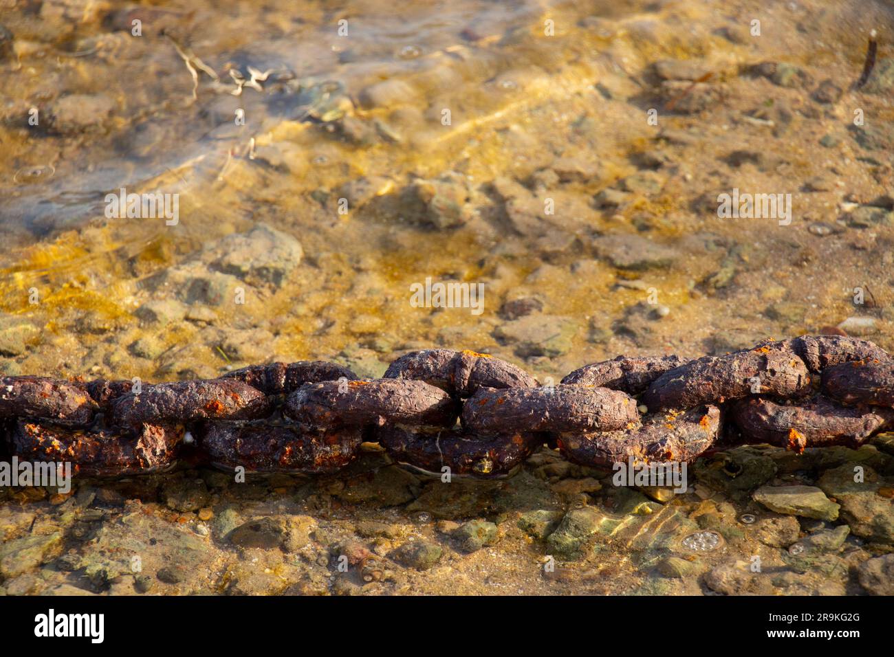 vecchia catena rugginita fissata a un muro di cemento in strada Foto Stock
