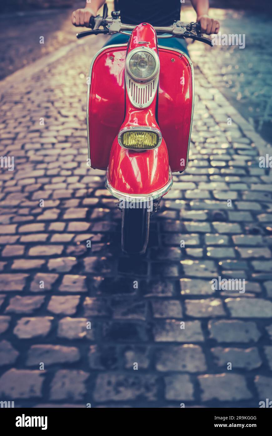Un uomo che cavalca Uno scooter o percorre Una strada acciottolata a Roma, Italia Foto Stock