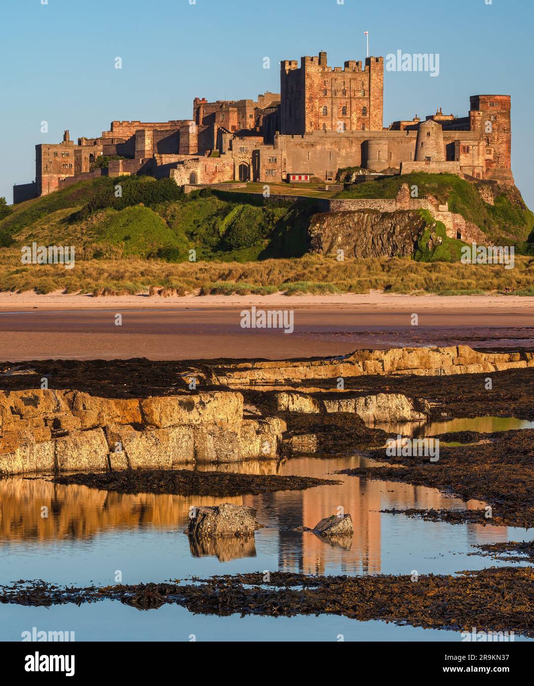 Vista del tramonto in estate del castello di Bamburgh e della spiaggia di Northumberland, Inghilterra nord-orientale, Regno Unito Foto Stock