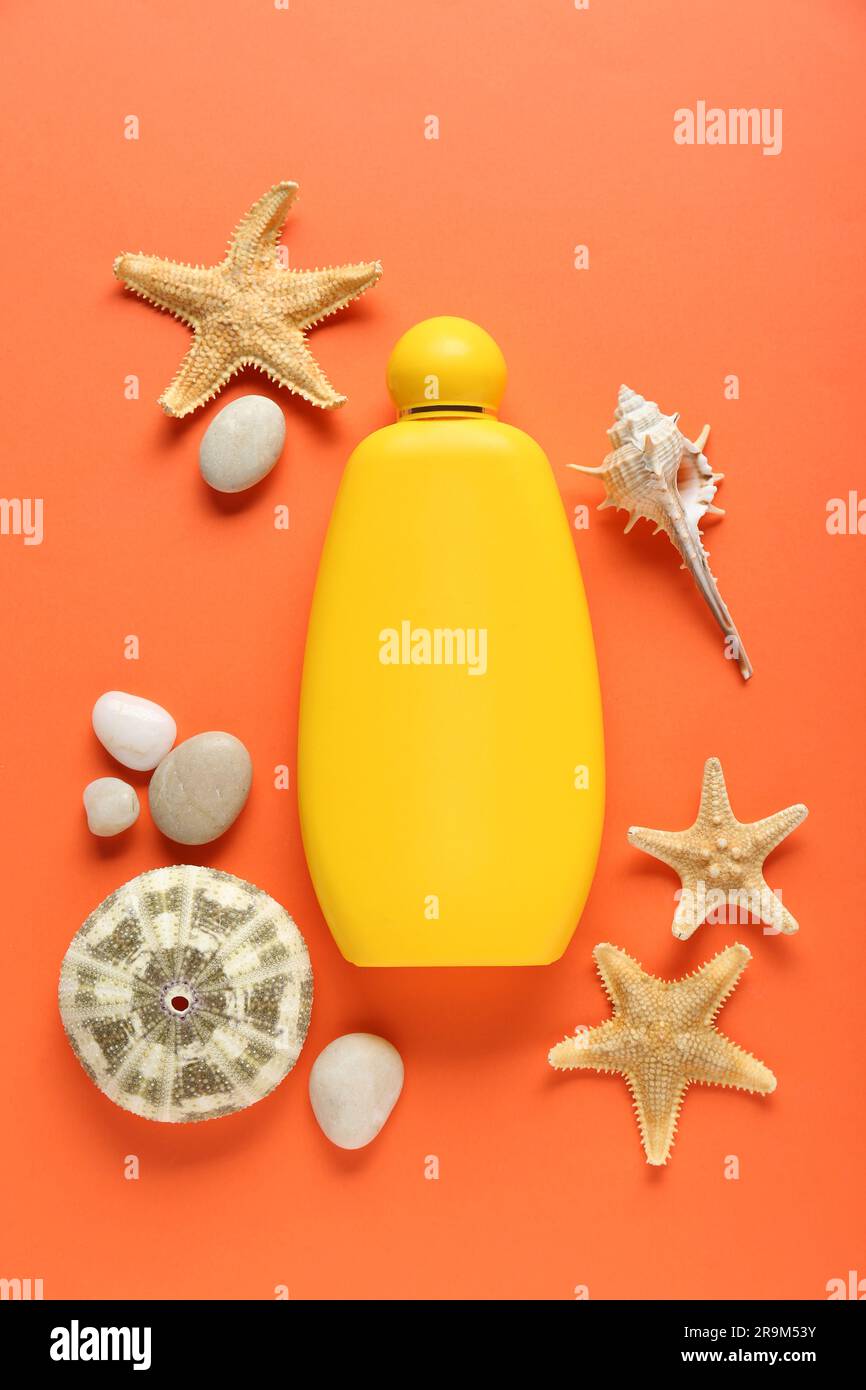 Bottiglia di crema di abbronzatura e conchiglie su sfondo arancione, piatto Foto Stock