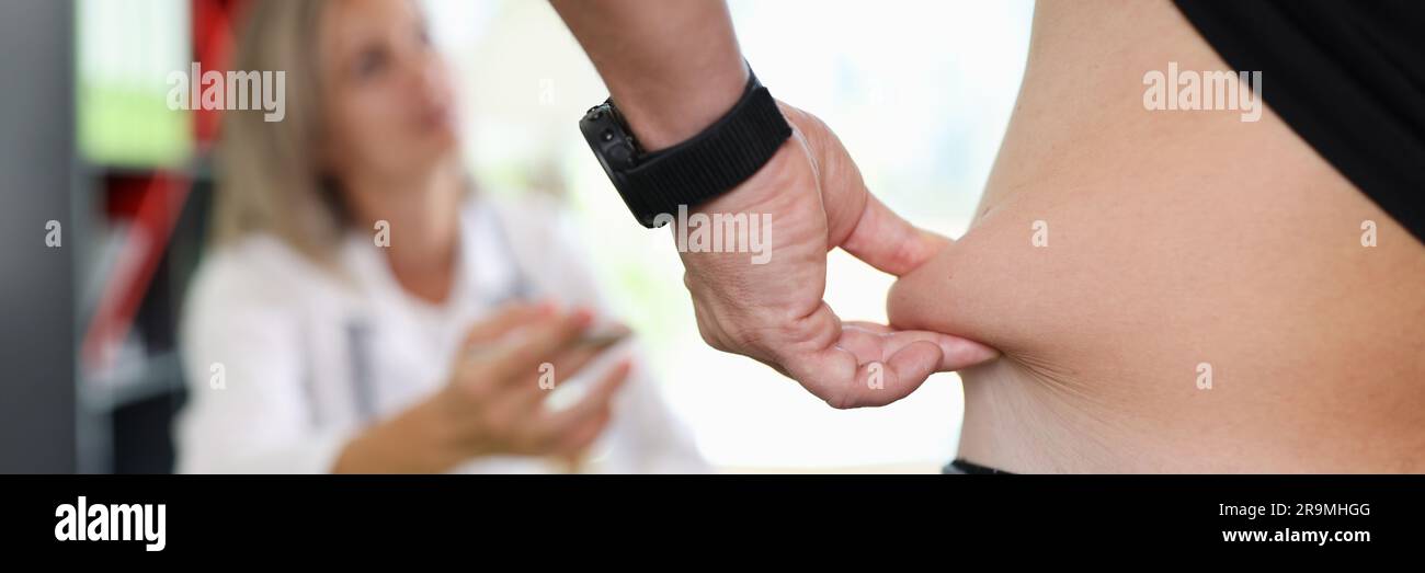 Uomo che tira la pelle sull'addome, mostrando il grasso corporeo nella zona addominale Foto Stock
