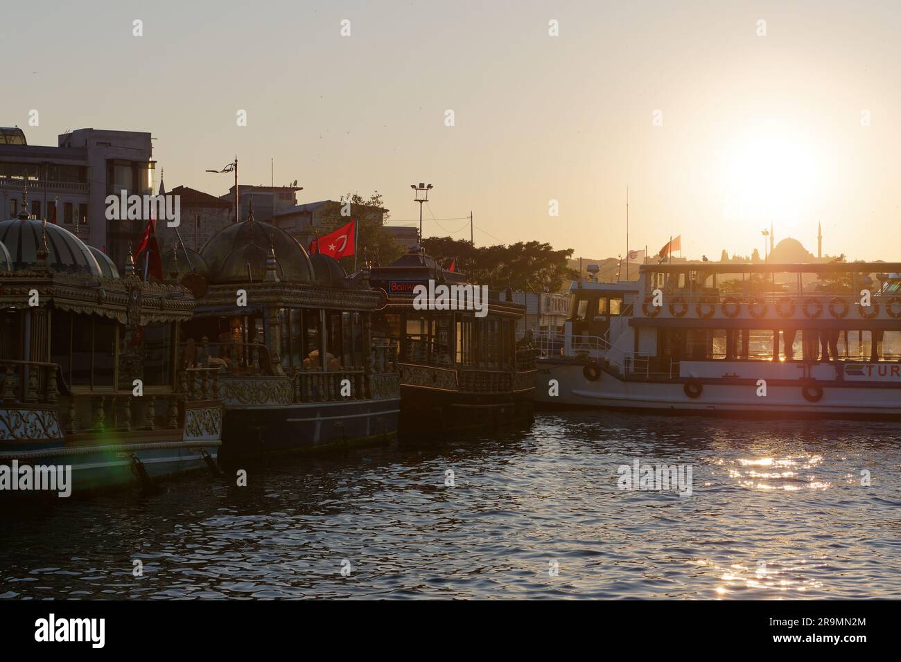 Barche con sandwich di pesce (Balık ekmek) e traghetto passeggeri sul fiume Corno d'Oro al tramonto estivo a Eminonu, Istanbul, Turchia. Foto Stock