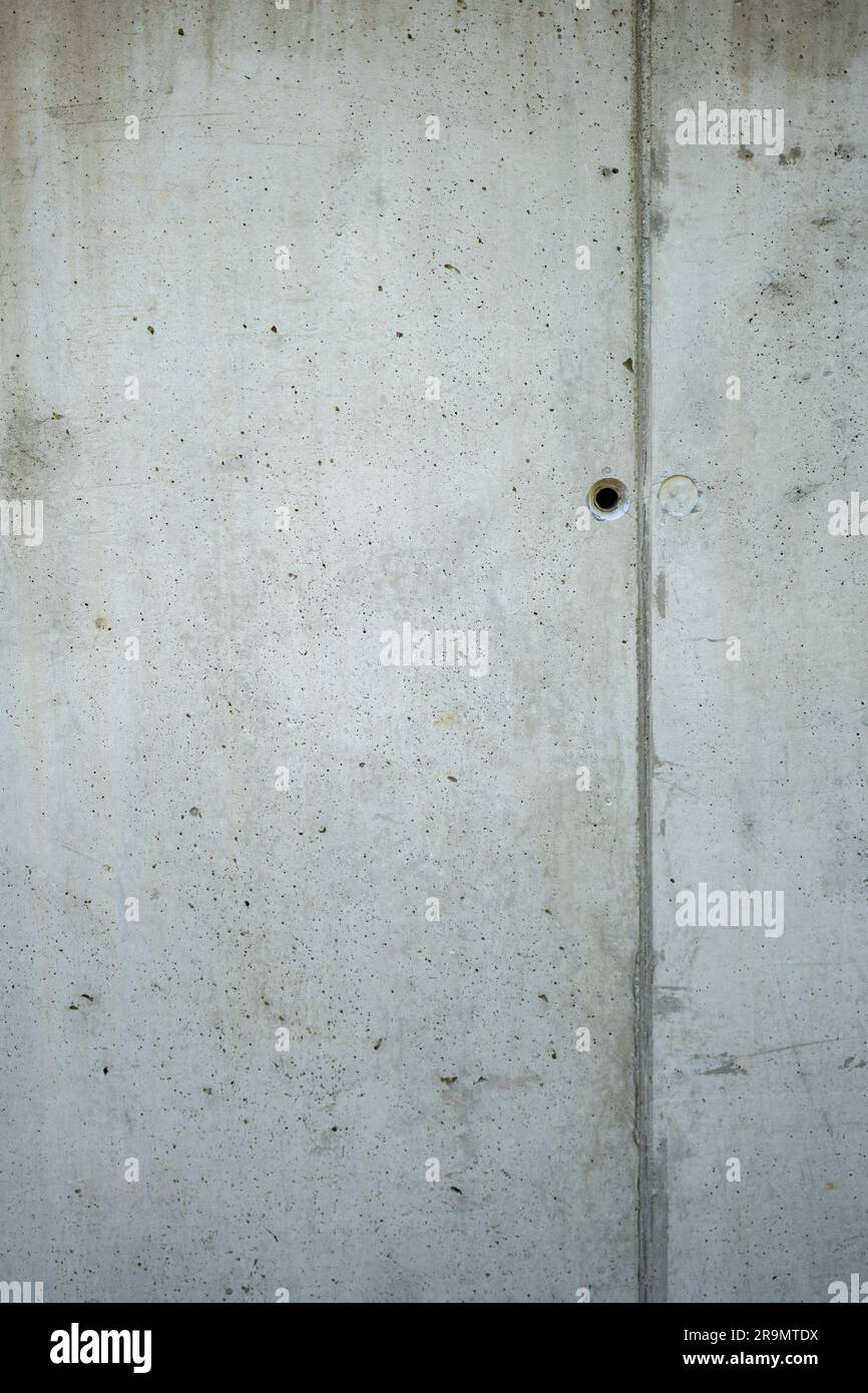 Parete architettonica in cemento. Fori di montaggio visibili e rotture tecnologiche dopo la cassaforma. Foto Stock