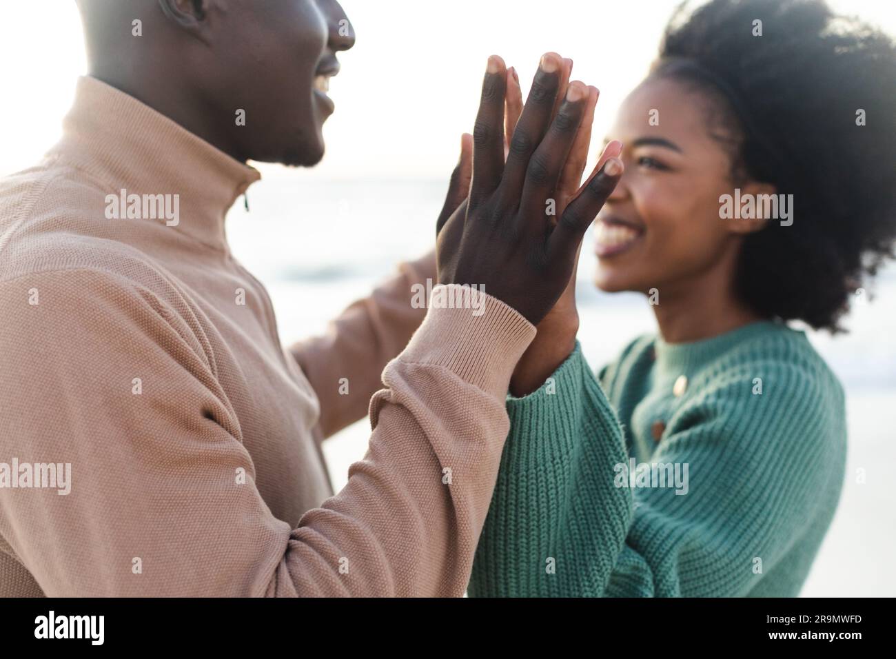 Felice coppia afroamericana che si tiene per mano e sorride sulla spiaggia Foto Stock