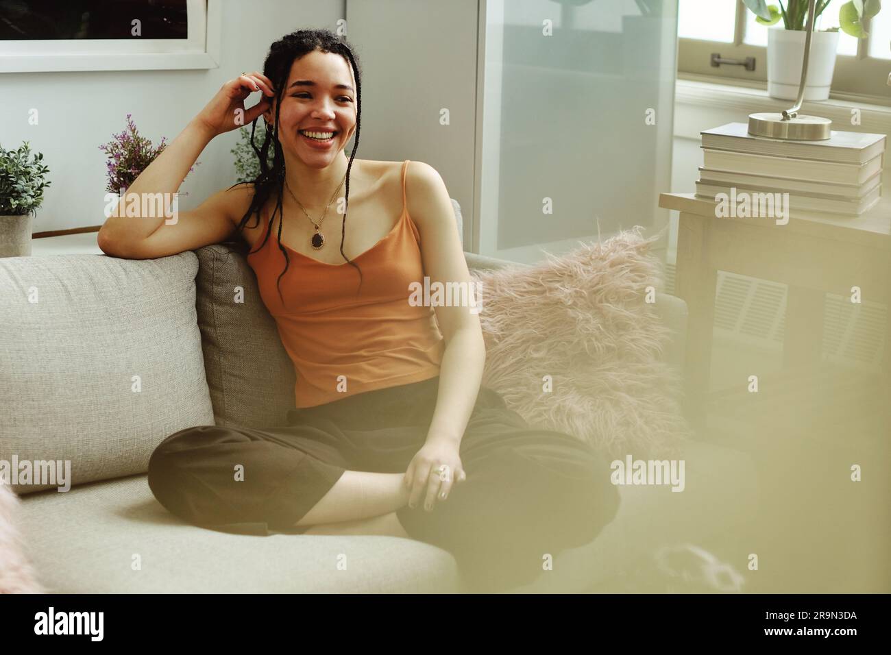 giovane donna di razza mista seduta in divano a casa Foto Stock