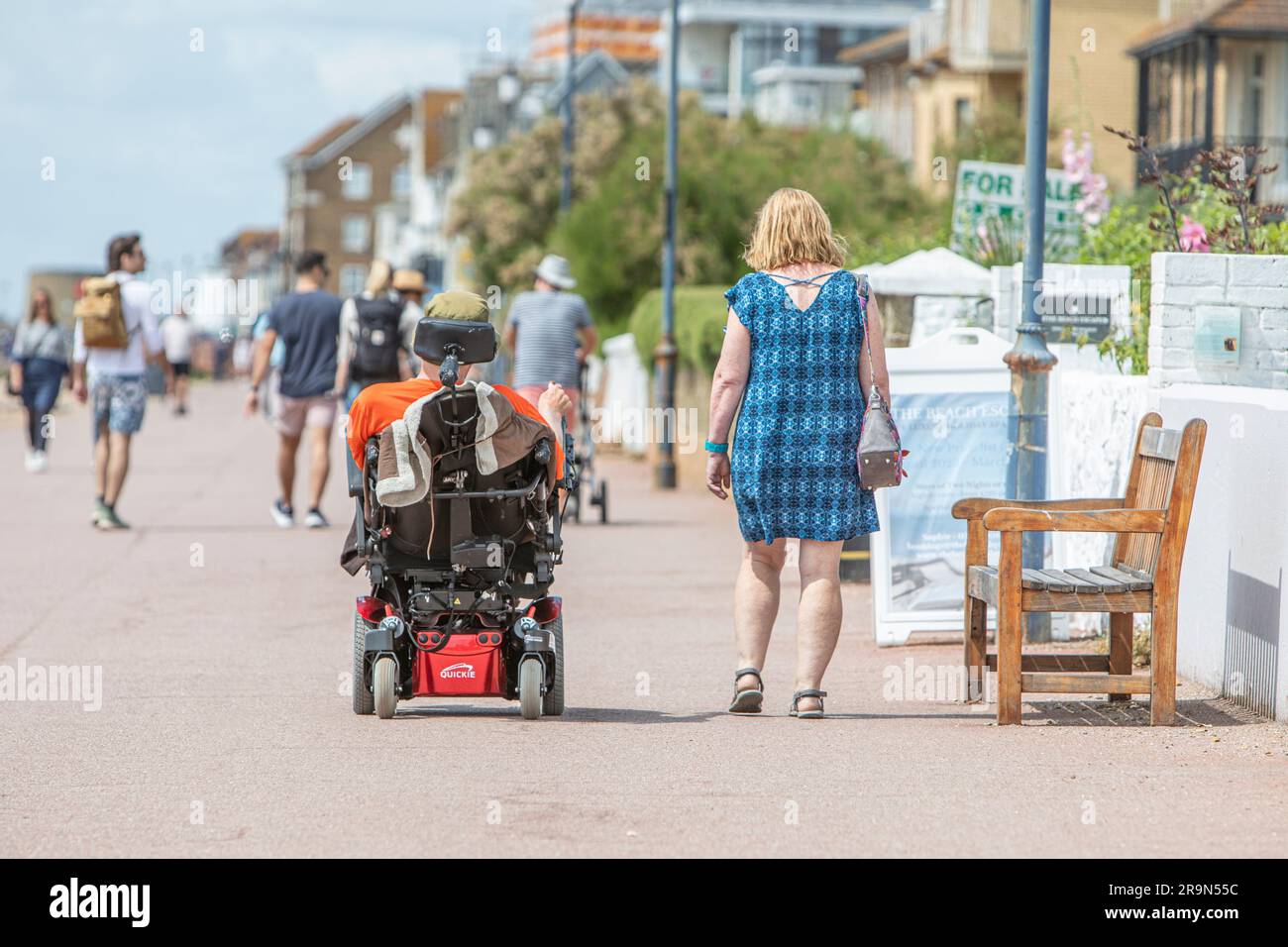 Una donna che cammina con un amico su uno scooter da mobilità in una giornata di sole. Foto Stock