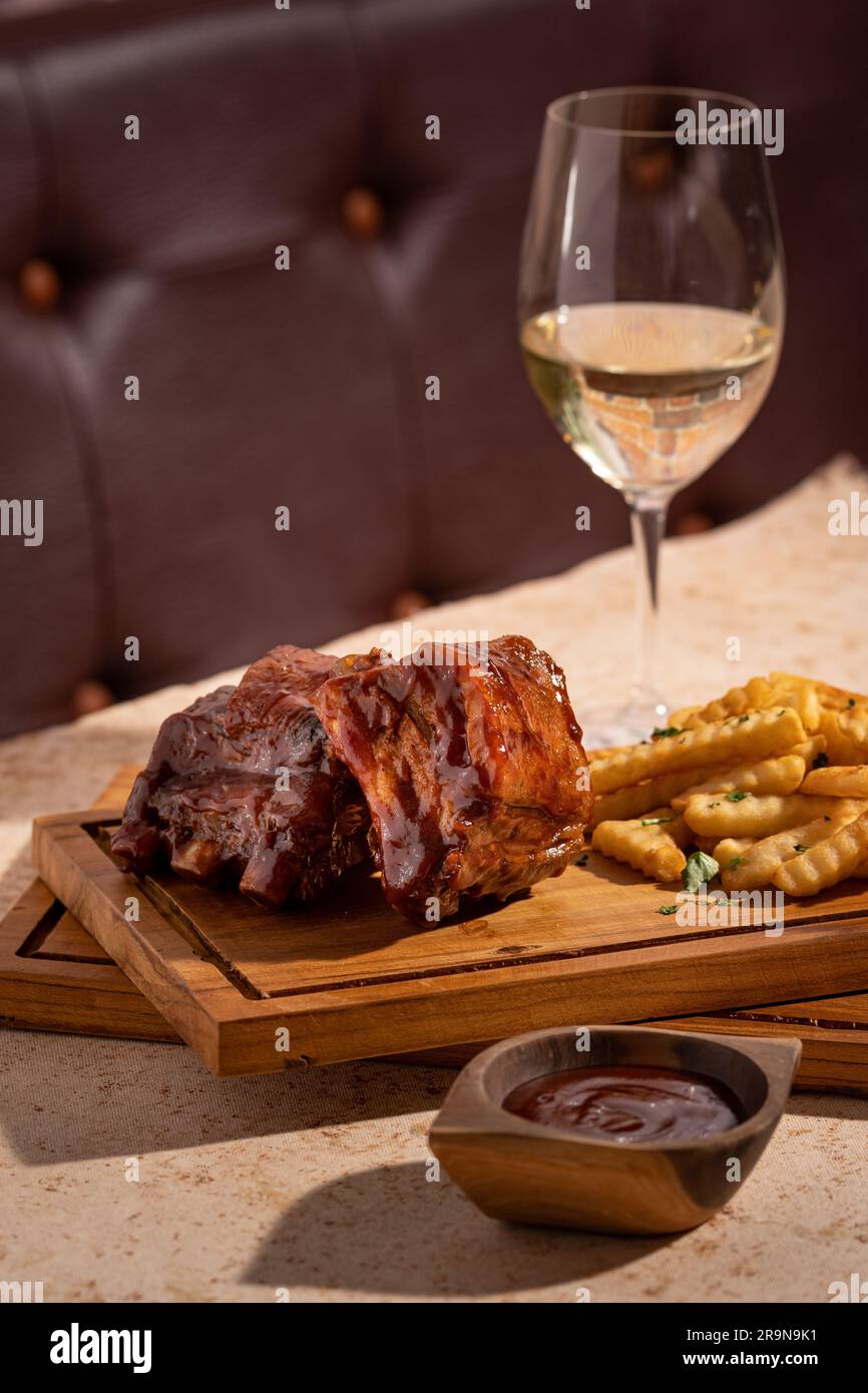 Un ambiente accogliente all'aperto con carne salata, patatine fritte e un bicchiere di vino Foto Stock