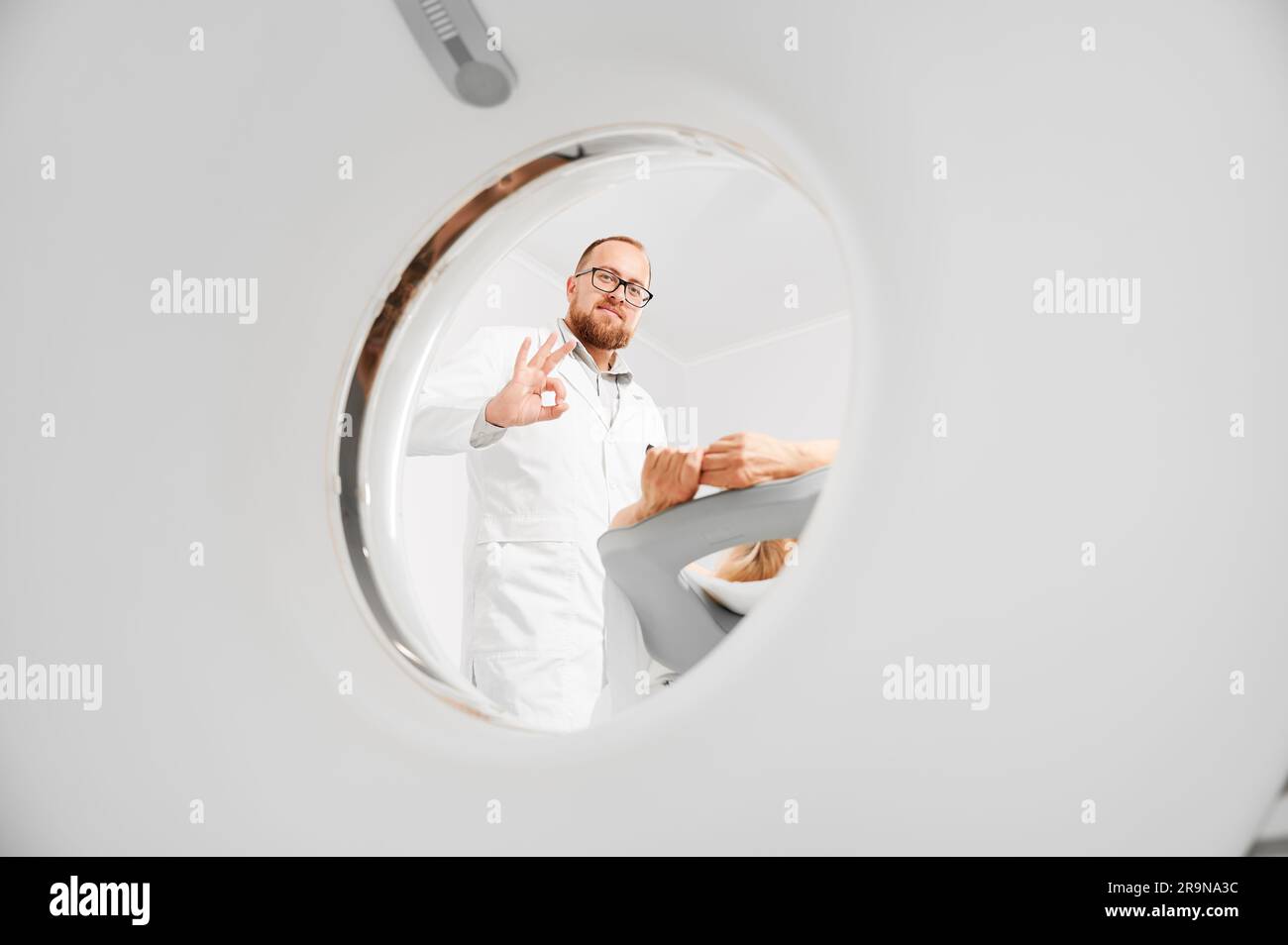 Tomografia computerizzata medica o scanner RM. Il radiologo maschile esamina la paziente femminile, mostrando il concetto di gesto corretto della diagnostica moderna. Foto Stock