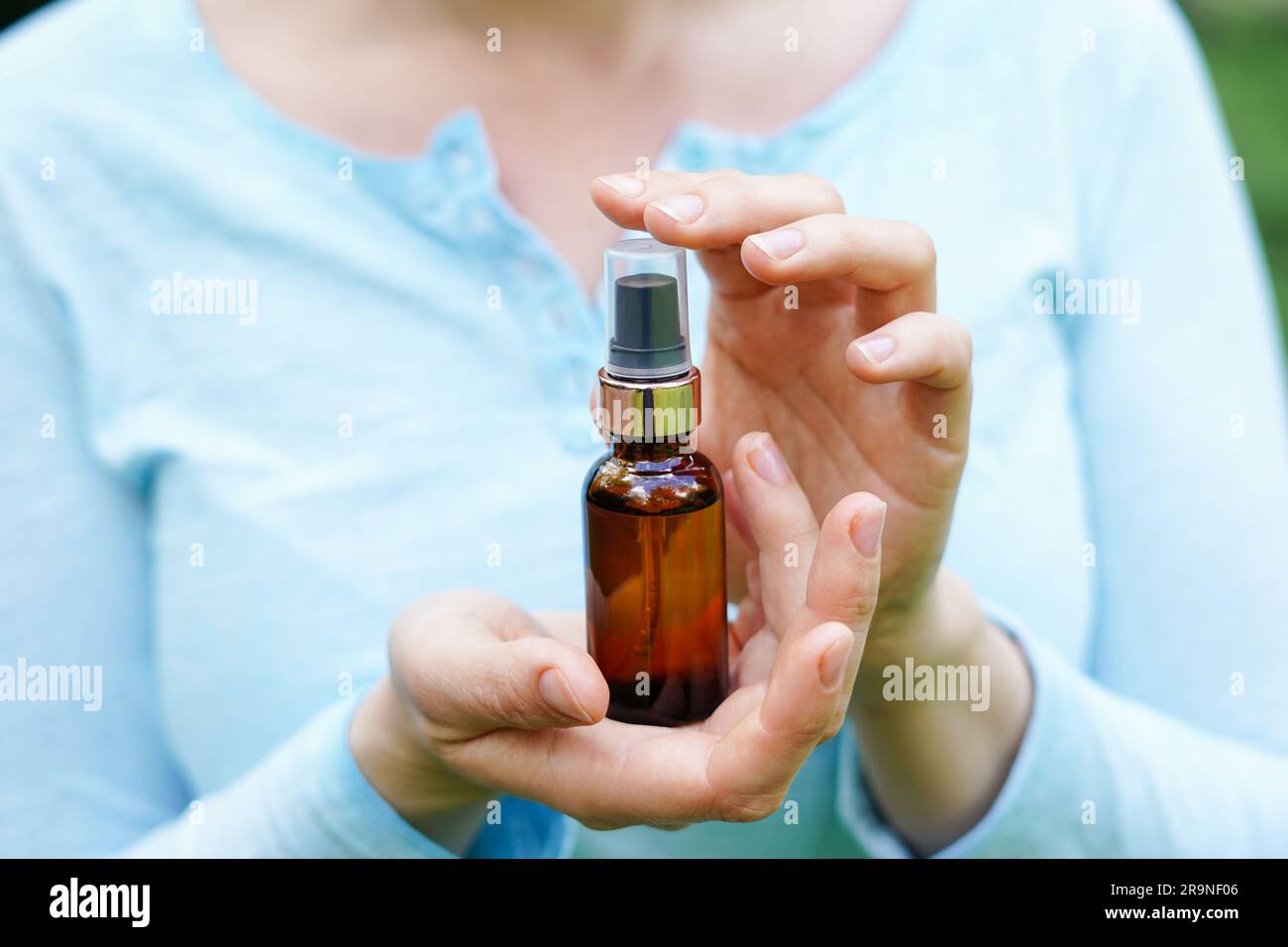 Donna in tessuto blu con bottiglia di vetro marrone con olio cosmetico spa. saloni terapeutici, prodotti naturali per la cura del corpo Foto Stock