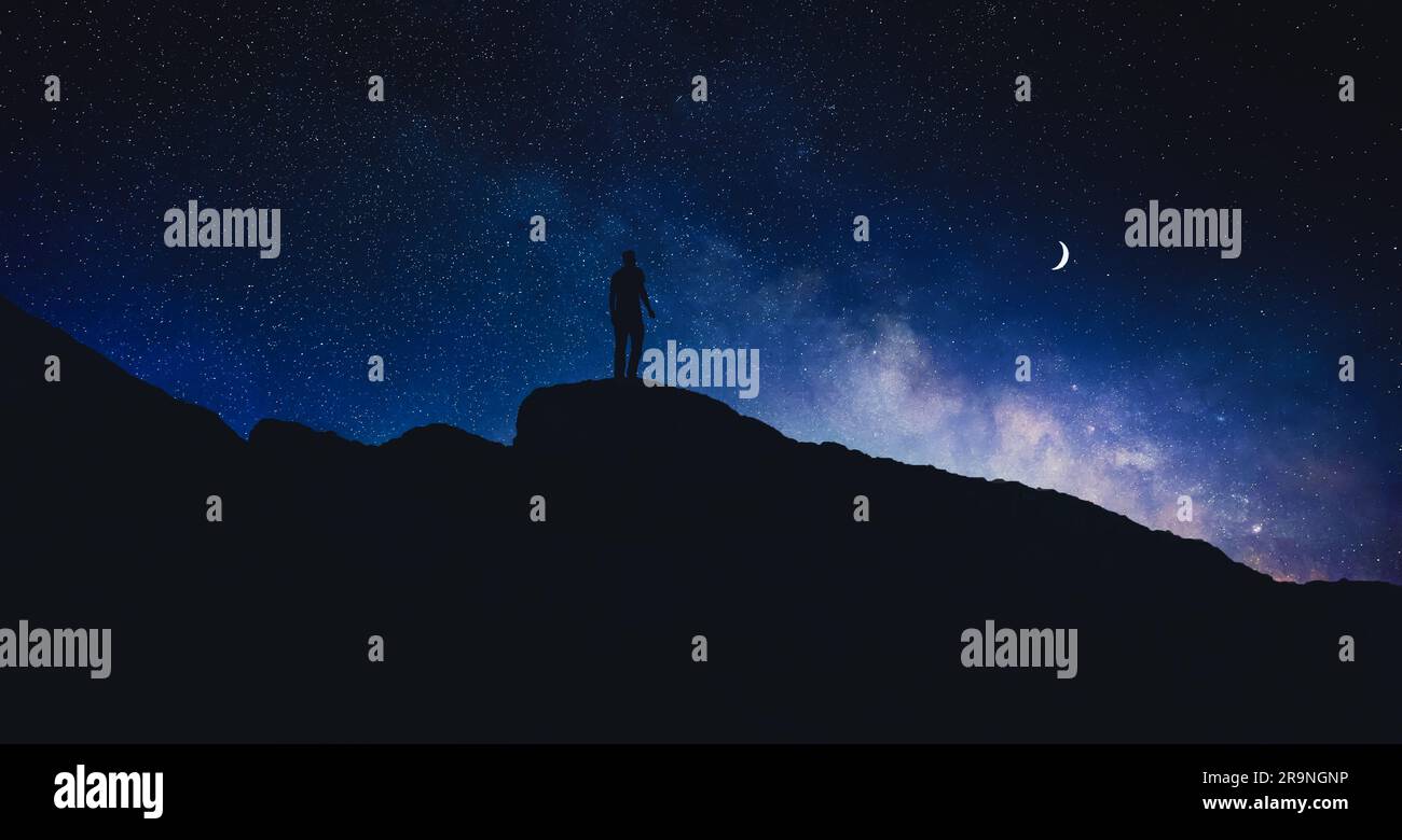 Silhouette di uomo in montagna sotto il bellissimo cielo stellato con luna a mezzaluna di notte, design striscione Foto Stock