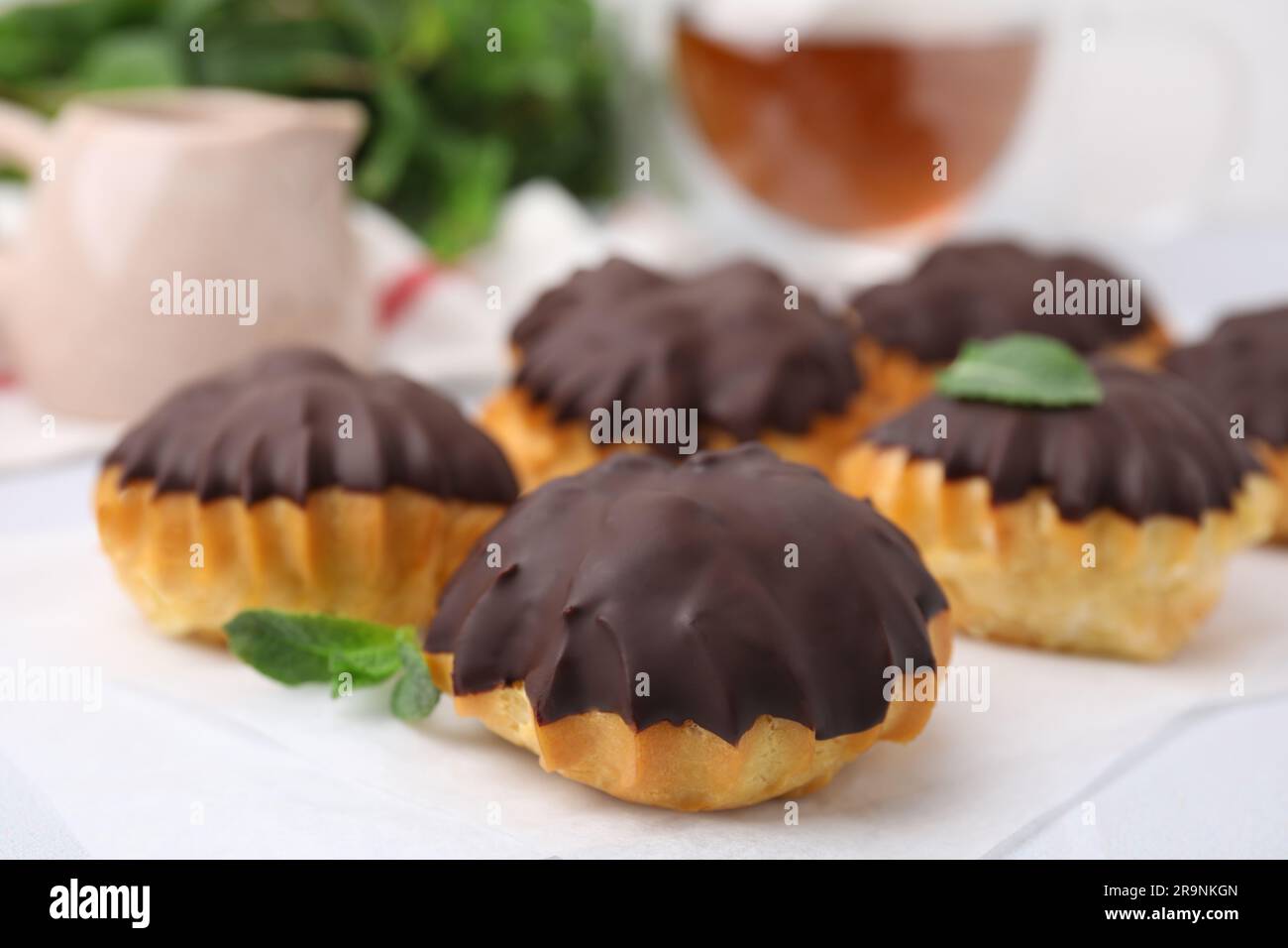 Deliziosi profiteroles con cioccolato spalmato sul tavolo, primo piano Foto Stock