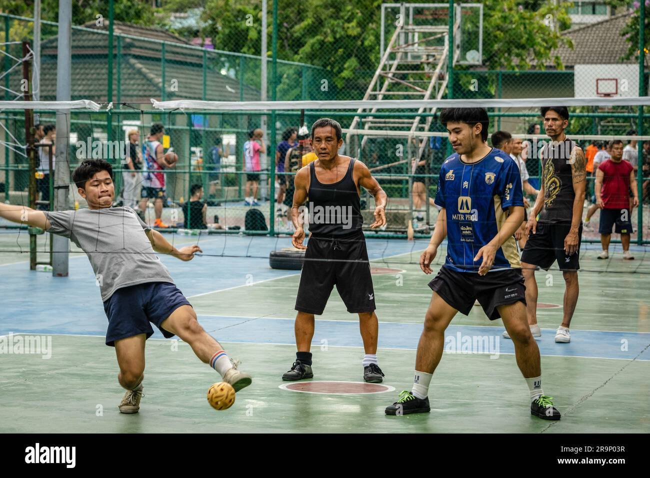 I residenti locali sono visti giocare a Sepak Takraw al Benchasiri Public Park in Sukhumvit Road. Sepak Takraw chiamato anche kick volley o pallavolo acrobatico della Thailandia è uno degli sport più popolari del sud-est asiatico che si gioca con una palla fatta di rattan o plastica sintetica dove i giocatori possono solo toccare la palla con i piedi, il corpo o la testa. Foto Stock