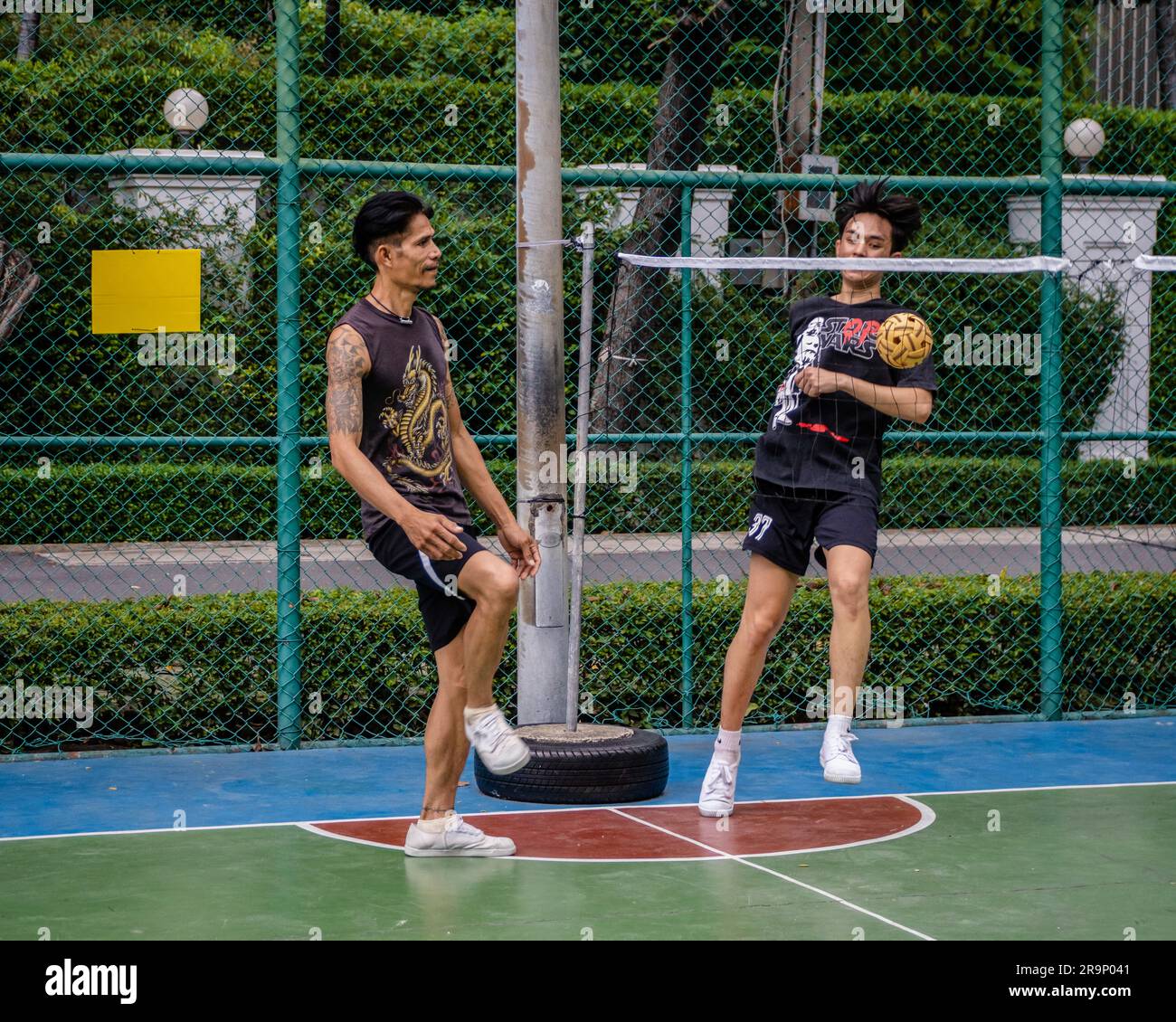 I residenti locali sono visti giocare a Sepak Takraw al Benchasiri Public Park in Sukhumvit Road. Sepak Takraw chiamato anche kick volley o pallavolo acrobatico della Thailandia è uno degli sport più popolari del sud-est asiatico che si gioca con una palla fatta di rattan o plastica sintetica dove i giocatori possono solo toccare la palla con i piedi, il corpo o la testa. Foto Stock