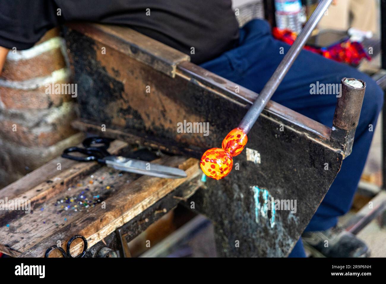 L'artigiano riscalda il vetro stampando il vetro con il metodo tradizionale di soffiatura del vetro, che è un'antica tecnica che forma e crea le bottiglie. GLA Foto Stock