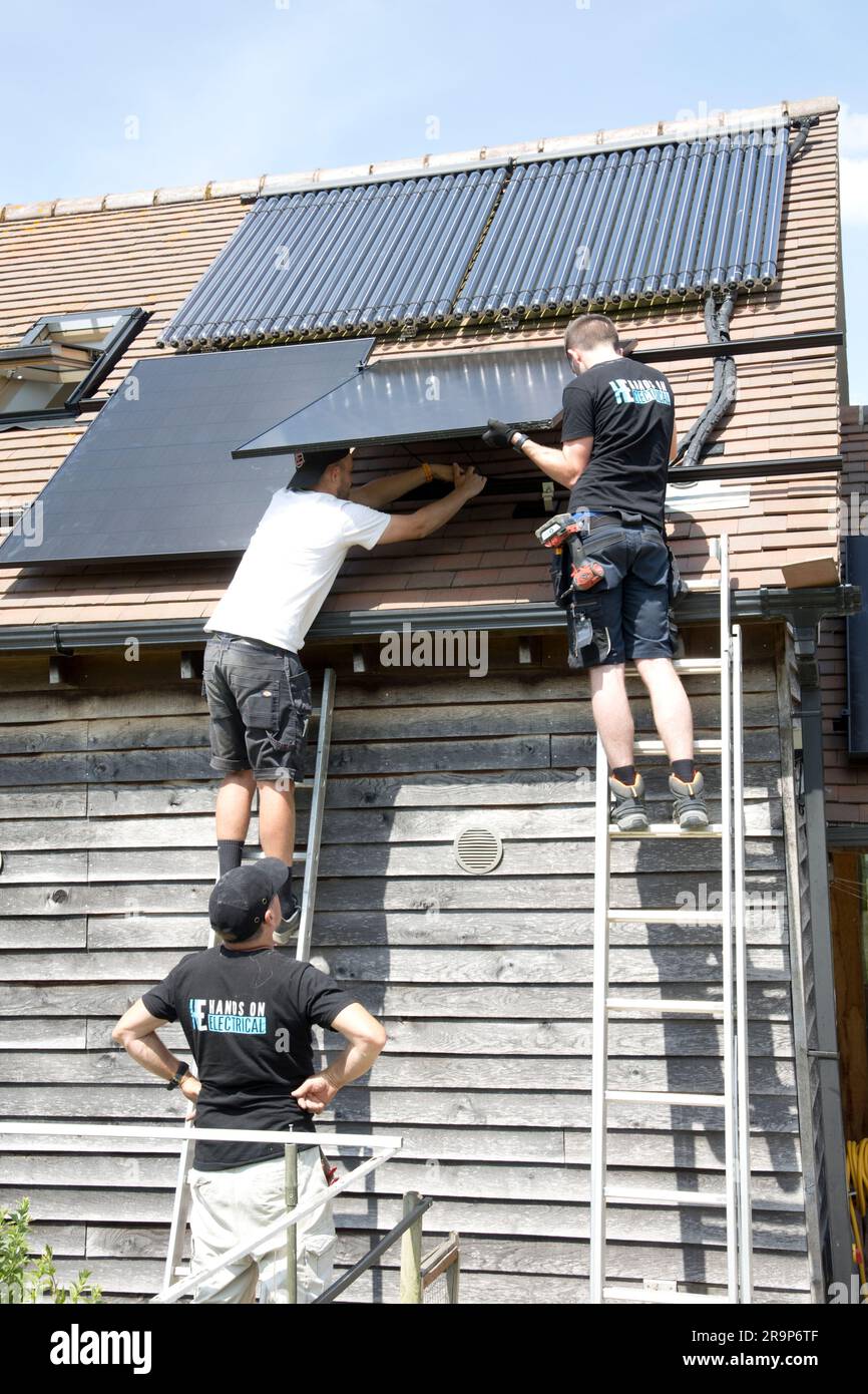 Due tecnici installano pannelli Perlite neri da 410 kW su tetti piastrellati che dispongono già di un set di tubi ET evacuati per il riscaldamento dell'acqua solare a Coleman Foto Stock