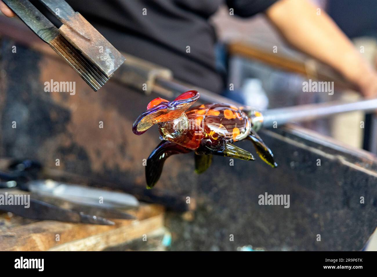 Artigiano che lavora, taglia, formatura e crea una tartaruga di vetro con il metodo tradizionale di soffiatura del vetro, che è una tecnica antica che forma Foto Stock