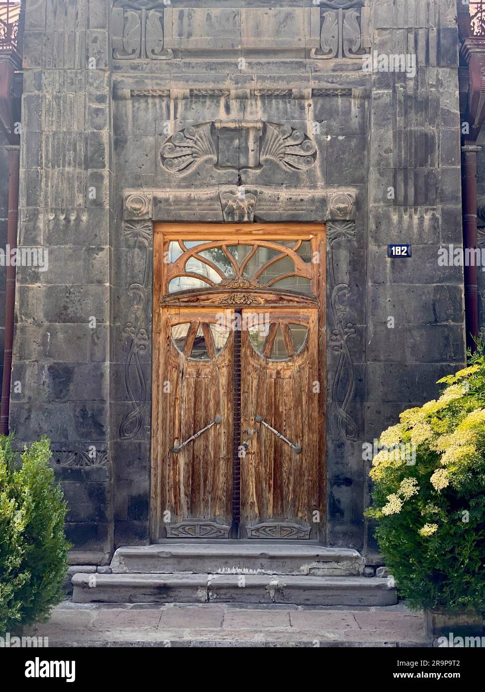 Una vecchia porta di legno di stile tradizionale fissata ad un antico edificio in pietra a Gyumri, Armenia. Foto Stock