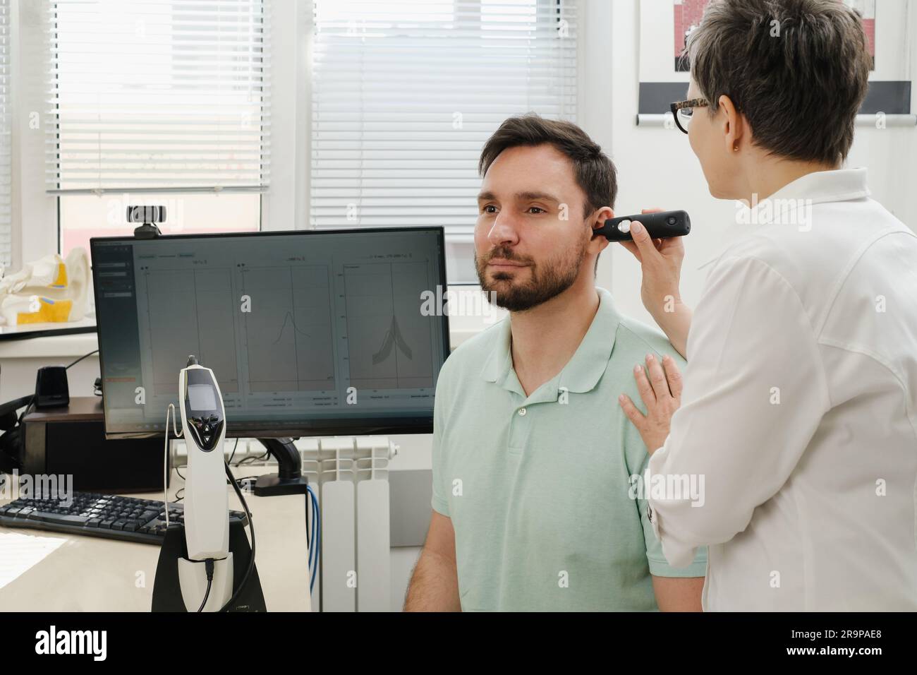 L'uomo ha un appuntamento alla clinica, controlla l'udito. Medico audiologo consulente presso una clinica di riabilitazione dell'udito per selezionare il dispositivo digitale per il centro Foto Stock