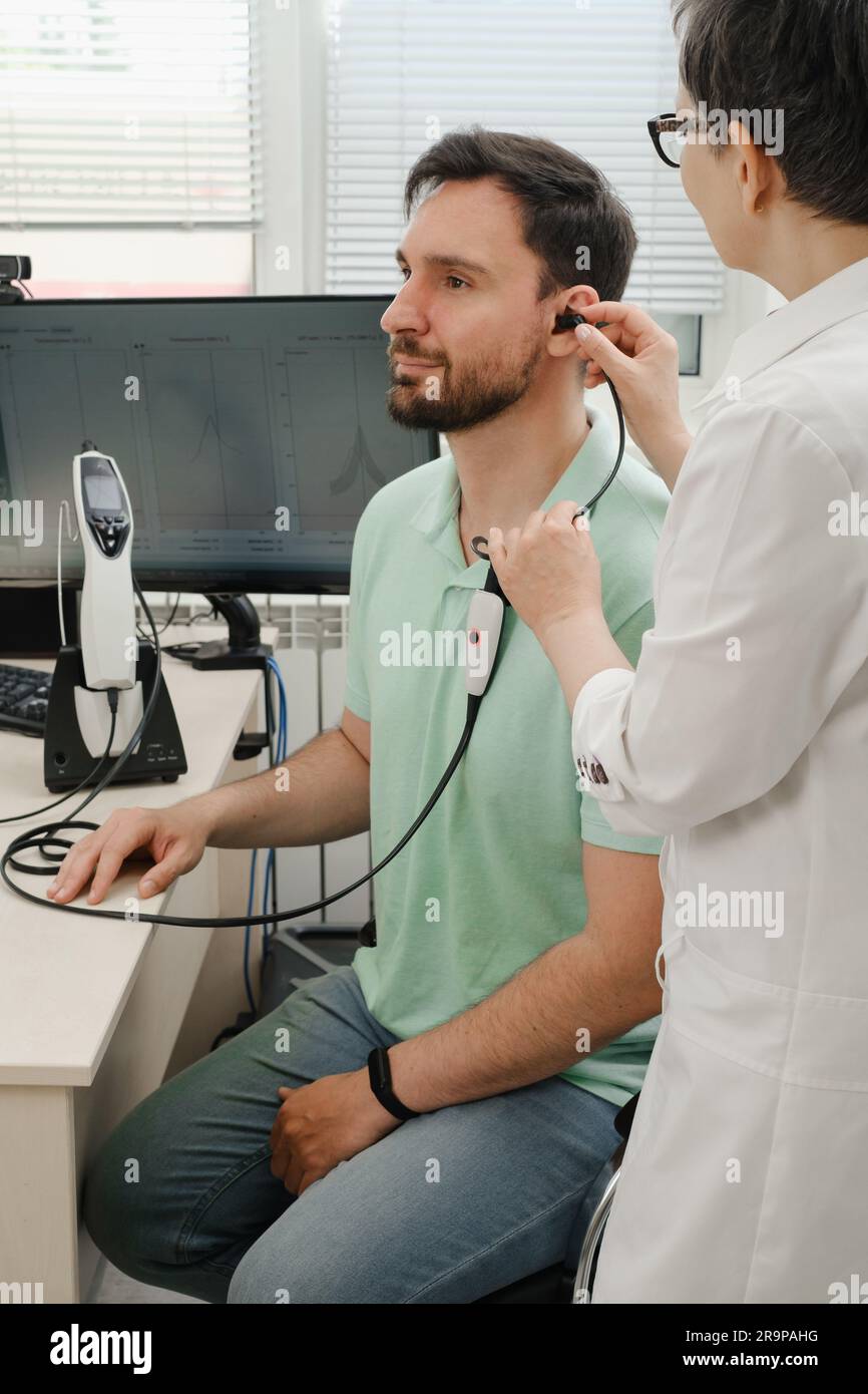 L'uomo ha un appuntamento alla clinica, controlla l'udito. Medico audiologo consulente presso una clinica di riabilitazione dell'udito per selezionare il dispositivo digitale per il centro Foto Stock