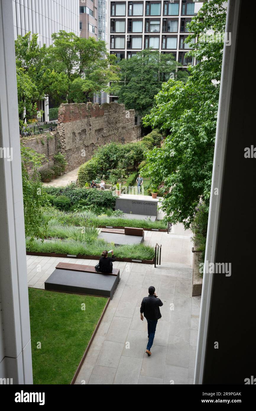 I lavoratori della città godono della relativa pace dalla moderna metropoli nel Giardino dei Salters sotto i resti dell'antico muro romano che un tempo costituiva il confine dell'antica città di Londinium, ma ora si trova nel 21° secolo Square Mile della City di Londra, Il distretto finanziario della capitale, il 27 giugno 2023, a Londra, in Inghilterra. Il muro romano fu costruito tra il 190 e il 225 come muro difensivo di pietra tortuosa intorno al lato terra della città. Il muro di Londra fu uno dei più grandi progetti di costruzione realizzati nella Britannia romana, che richiedeva da qualche parte nella regione di 85.000 tonnellate di stracci kentish Foto Stock