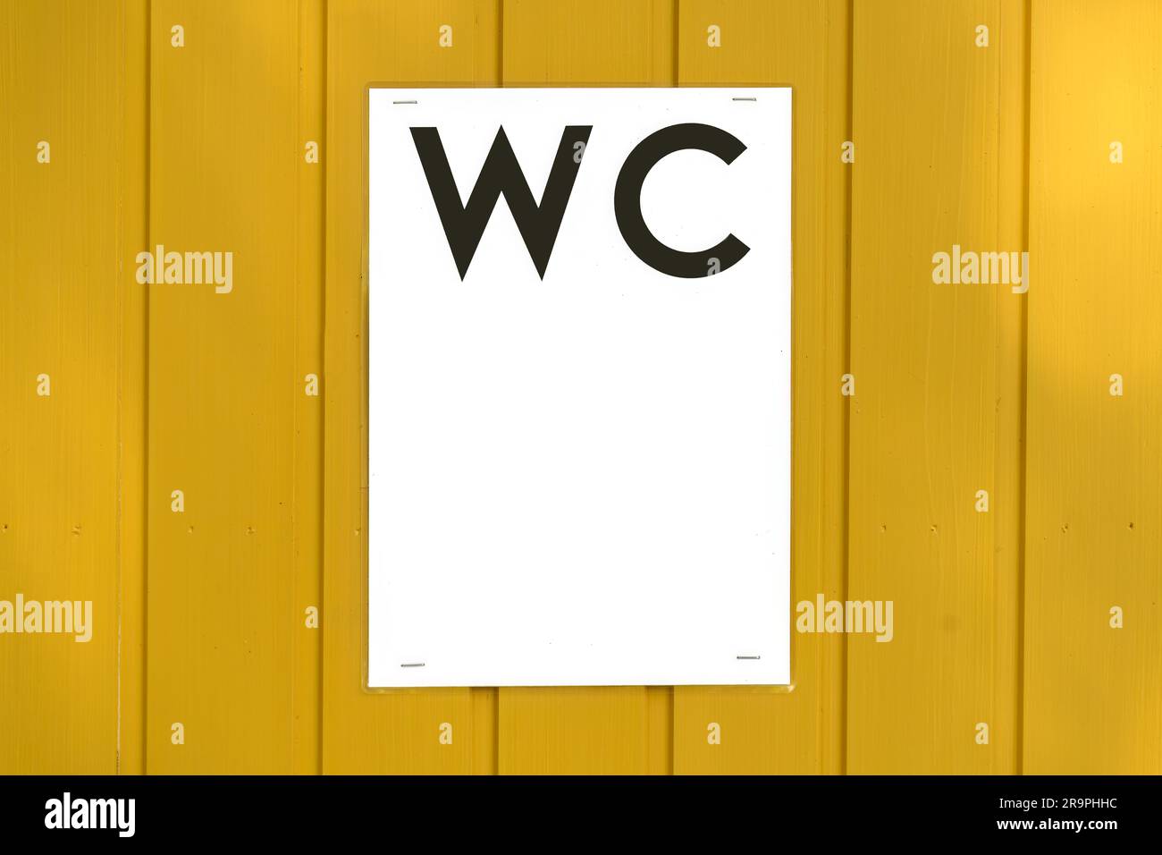 Cartello WC laminato fissato sullo sportello di legno giallo, primo piano con spazio per le copie Foto Stock