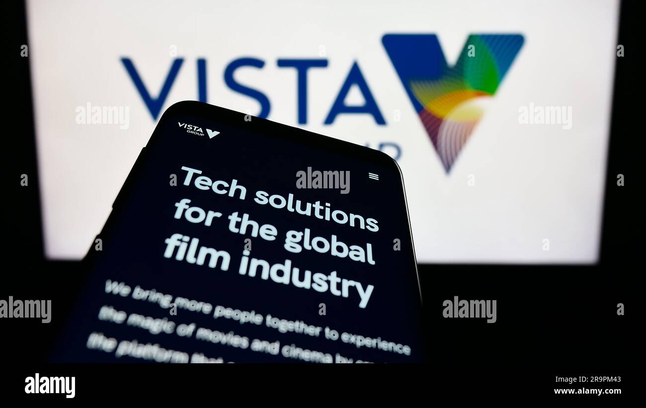 Telefono cellulare con sito Web della società Vista Group International Limited sullo schermo davanti al logo aziendale. Mettere a fuoco in alto a sinistra sul display del telefono. Foto Stock