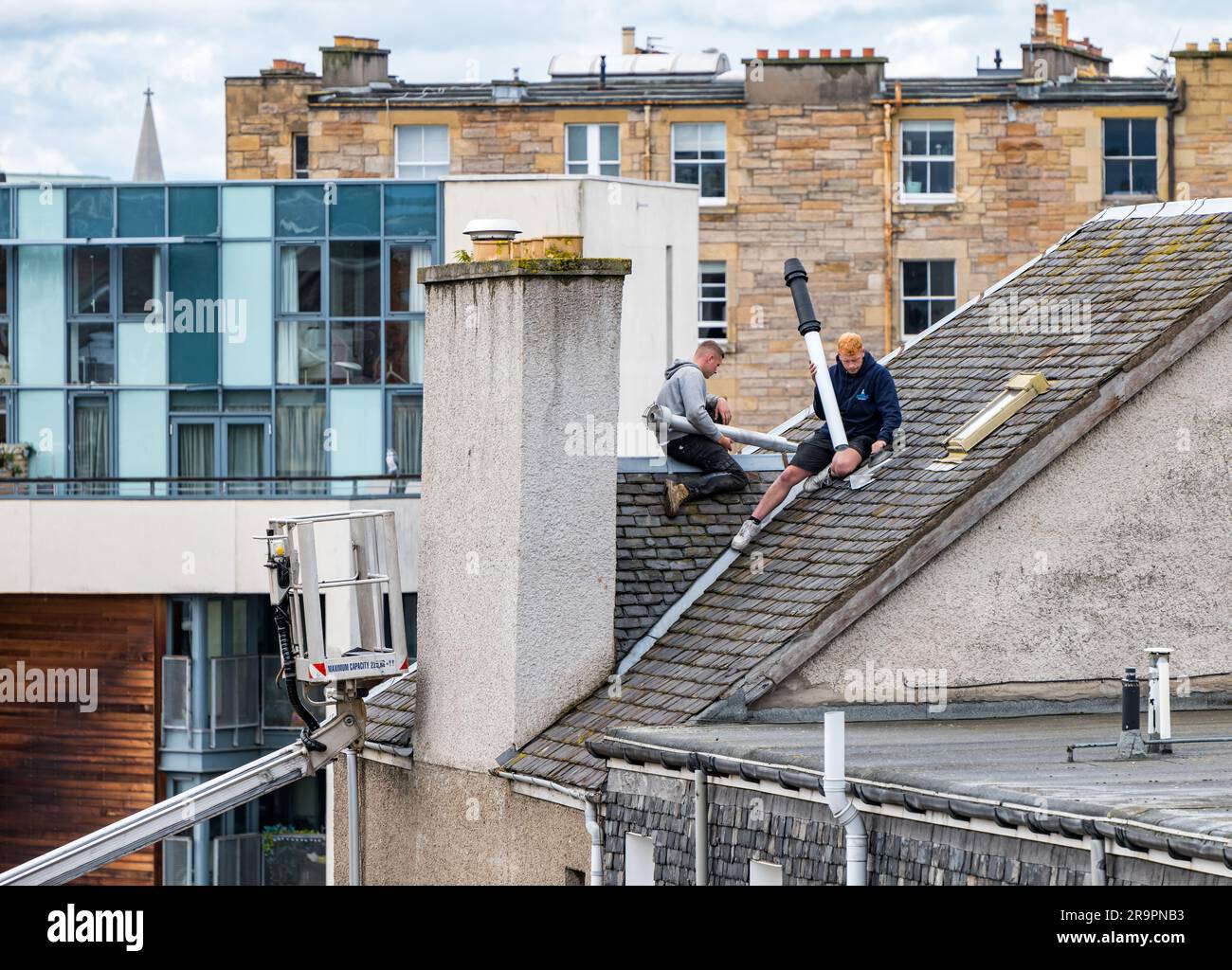 Operai nel raccoglitore ciliegie che sostituisce la bocchetta del tetto, Leith, Edimburgo, Scozia, Regno Unito Foto Stock