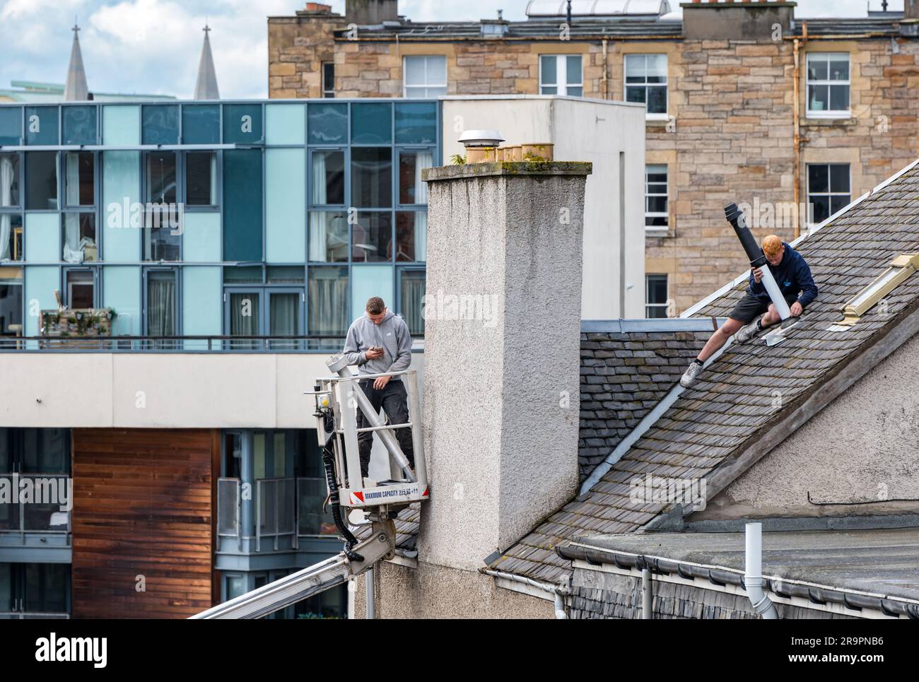 Operai nel raccoglitore ciliegie che sostituisce la bocchetta del tetto, Leith, Edimburgo, Scozia, Regno Unito Foto Stock