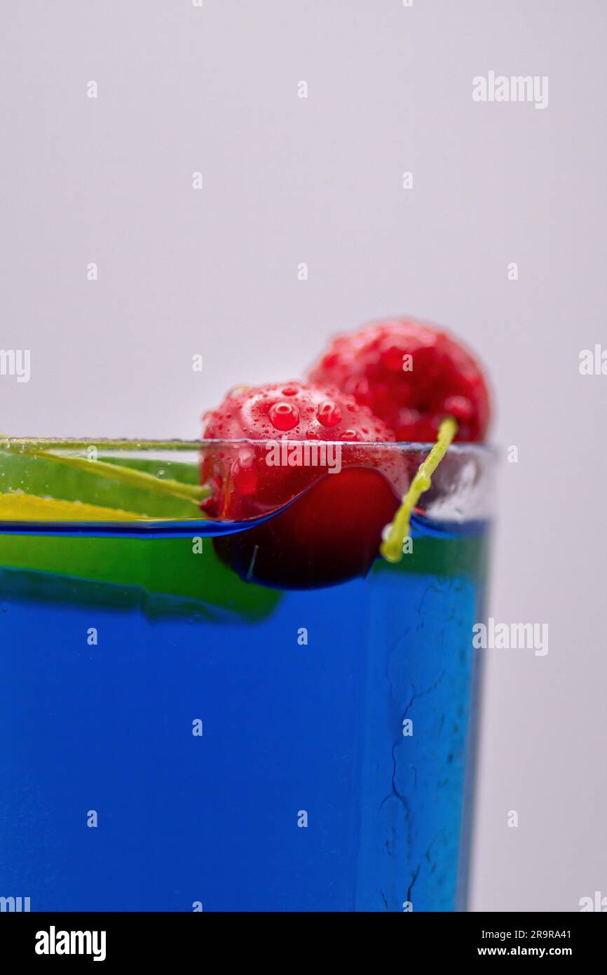Tropical Azure: Una bevanda blu adornata con primi piani di ghirlande di frutta fresche e succose Foto Stock