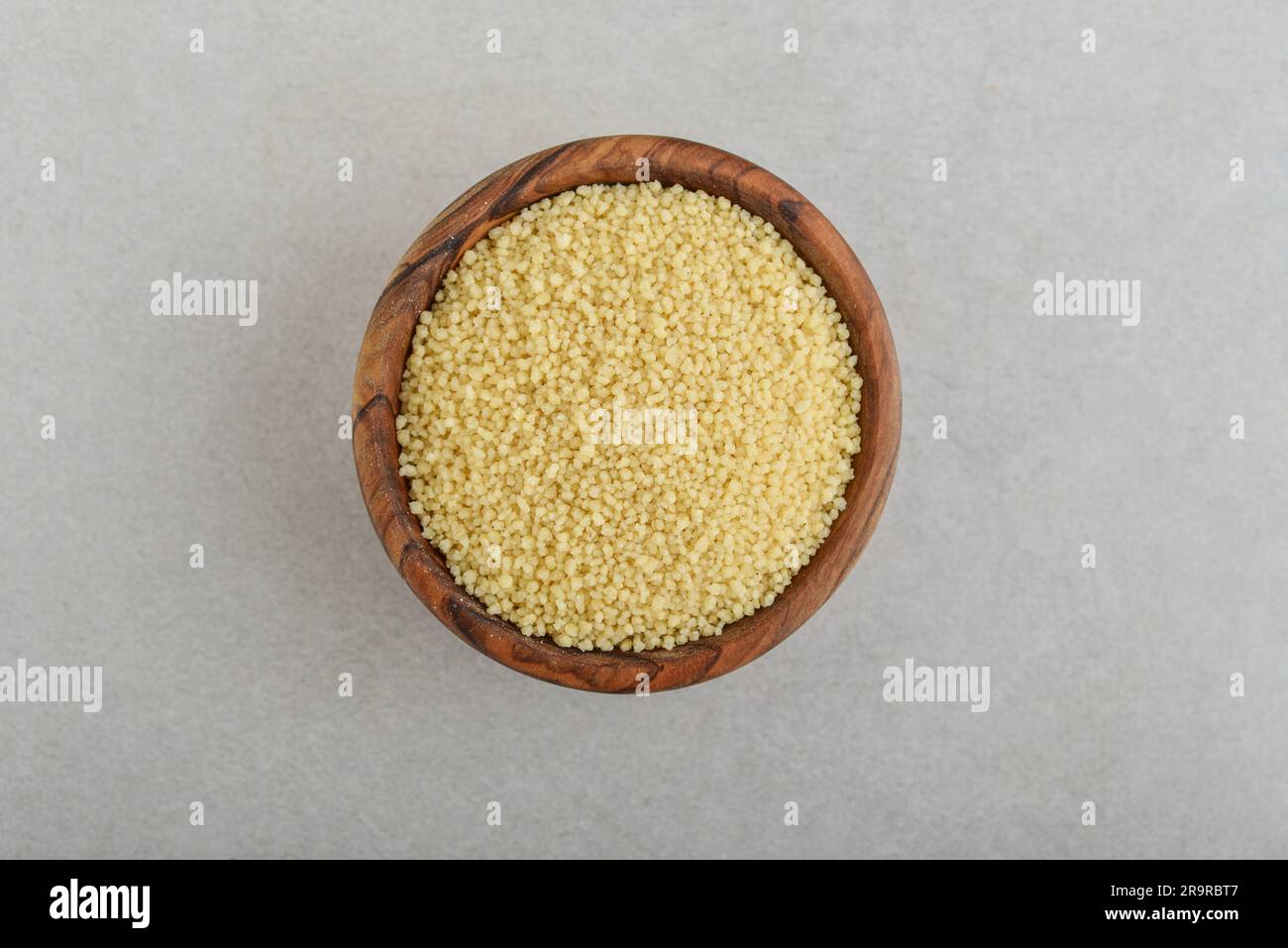 Couscous crudo in un recipiente di legno su fondo di cemento. Vista dall'alto Foto Stock