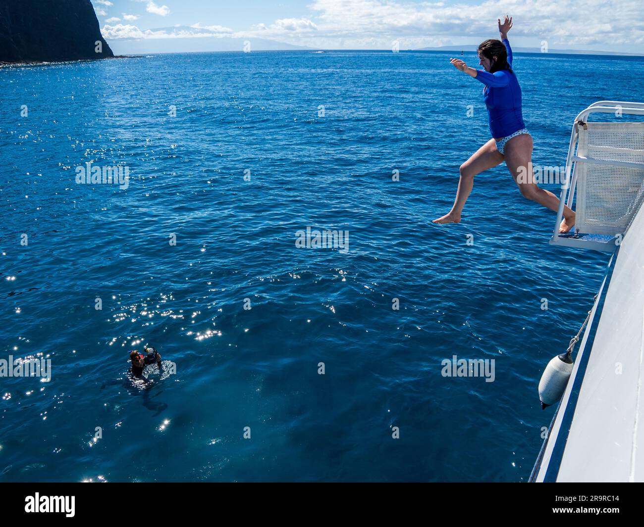 Le persone saltano con gioia da una barca nelle calde e limpide acque dell'Oceano Pacifico al largo delle coste di Lanai, Hawaii Foto Stock