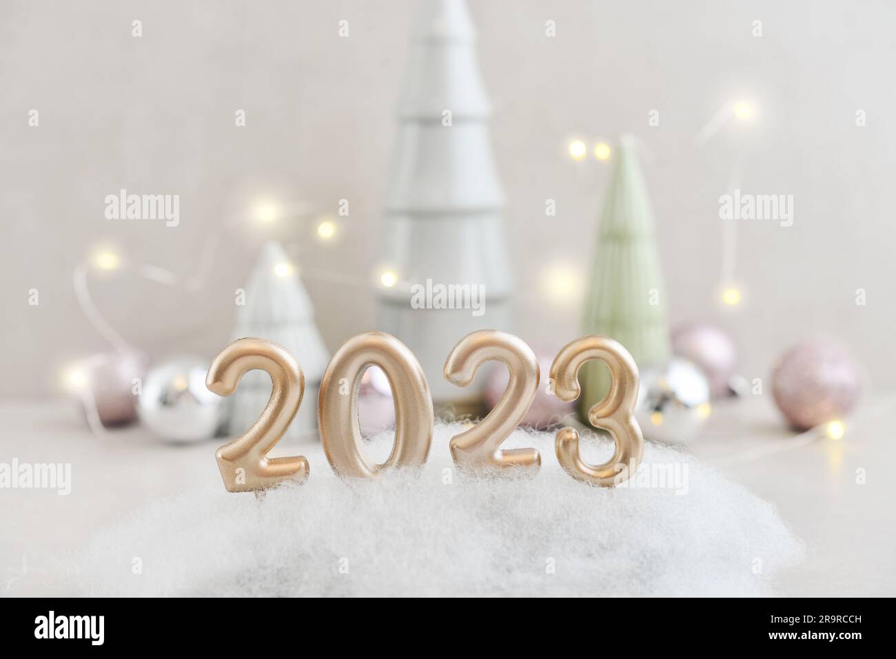 Abeti decorativi in ceramica con palline di natale e candele dorate a forma di numero 2023 Foto Stock