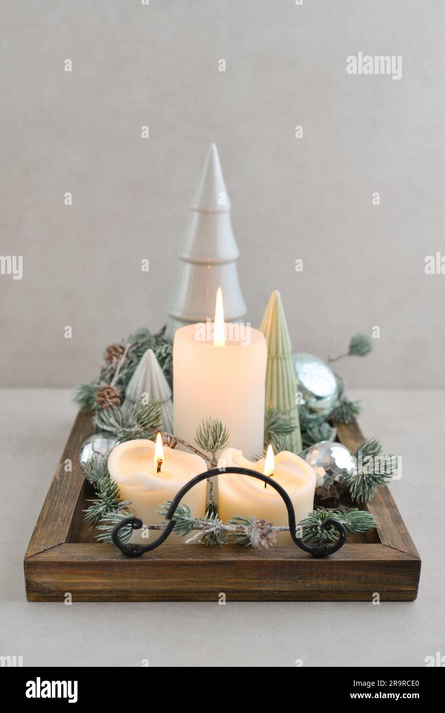 Abeti decorativi in ceramica con palline di natale blu e candele su vassoio di legno su sfondo di legno scuro Foto Stock