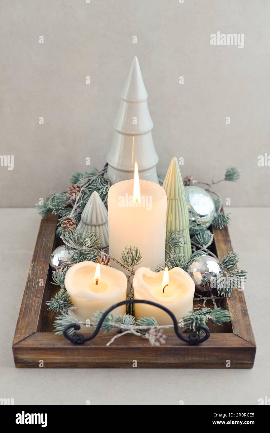 Abeti decorativi in ceramica con palline di natale blu e candele su vassoio di legno su sfondo di legno scuro Foto Stock