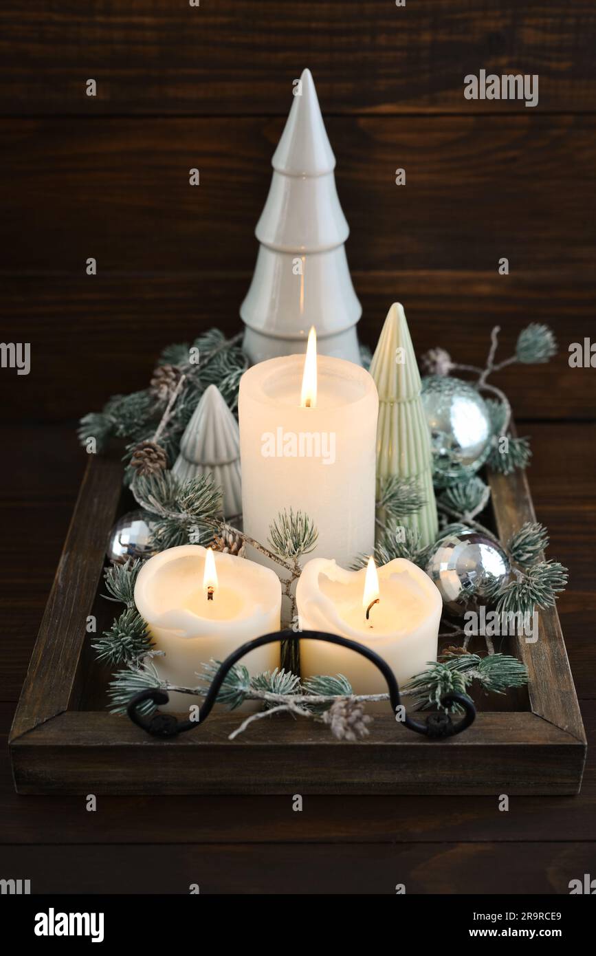 Abeti decorativi in ceramica con palline di natale blu e candele su vassoio di legno su sfondo di legno scuro Foto Stock