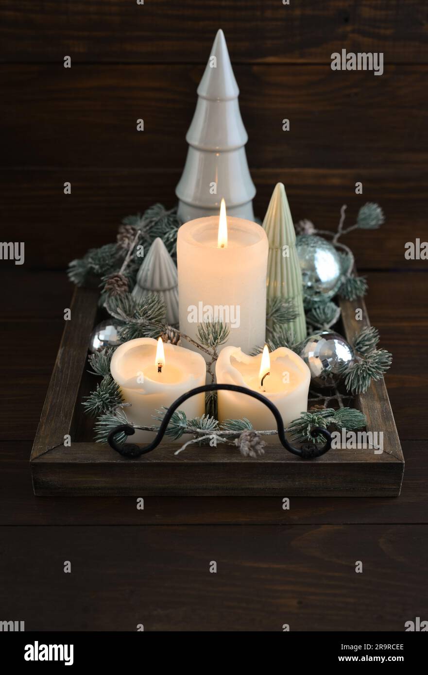 Abeti decorativi in ceramica con palline di natale blu e candele su vassoio di legno su sfondo di legno scuro Foto Stock