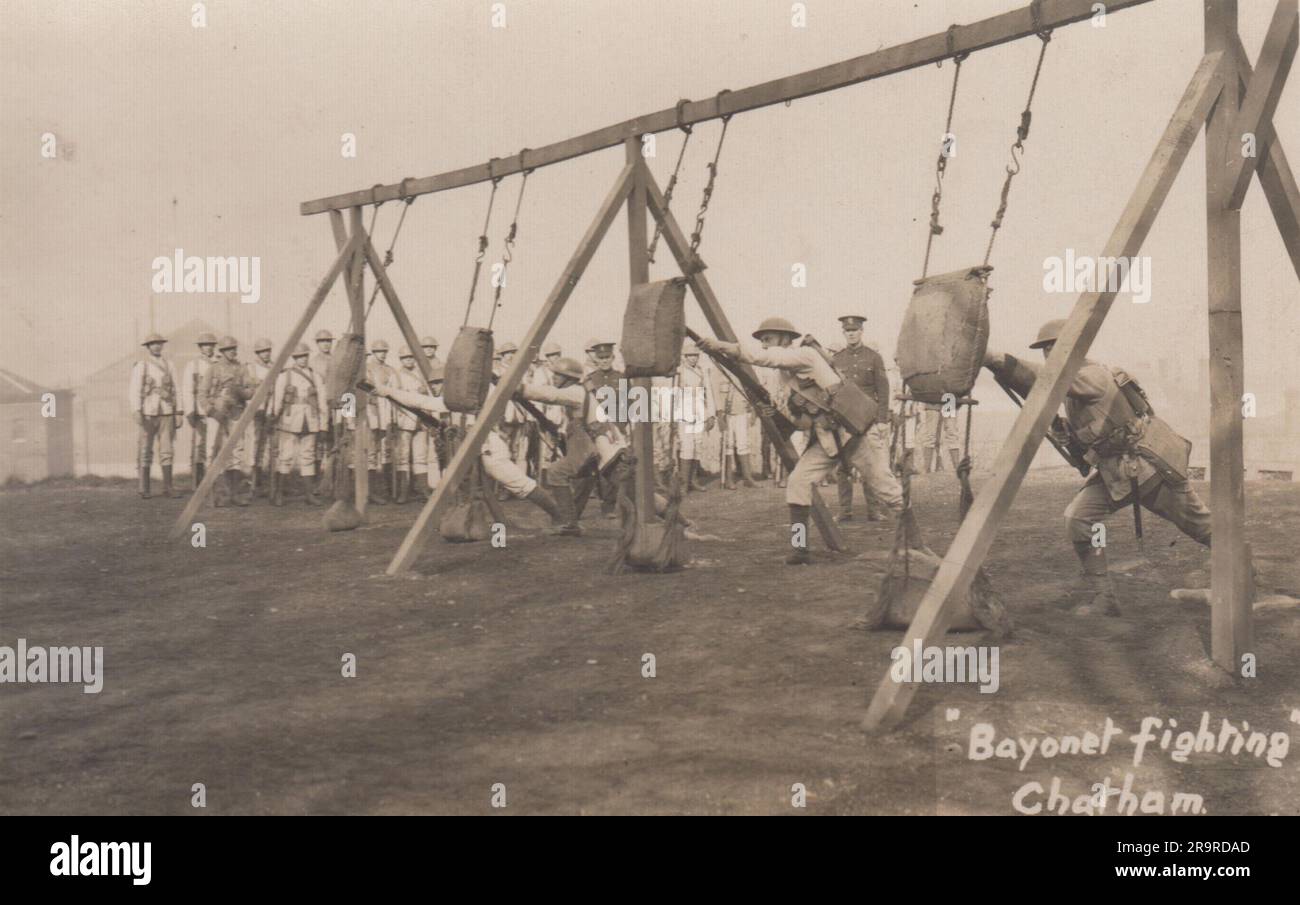 Combattimenti a baionetta a Chatham: Foto dell'era della prima guerra mondiale di soldati britannici che praticano il combattimento corpo a corpo. La foto mostra quattro uomini che lanciano baionette in sacchi di sabbia sospesi da una cornice, mentre il resto dell'unità e due sergenti in uniforme guardano Foto Stock